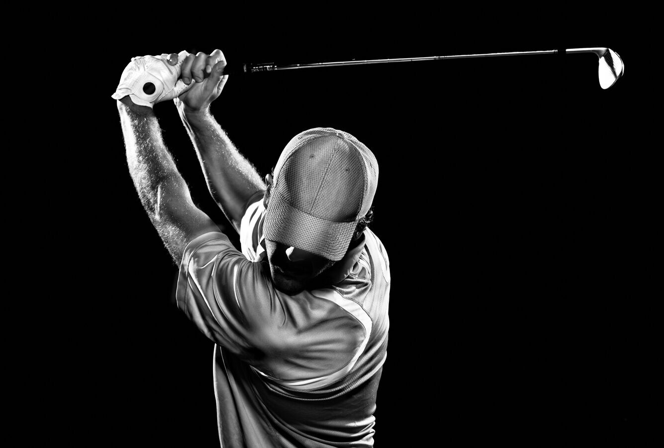 Schwarz-Weiß-Aufnahme eines Golfspielers beim Abschlag vor schwarzem Hintergrund Schwarz-Weiß-Aufnahme eines Golfspielers beim Abschlag vor schwarzem Hintergrund
