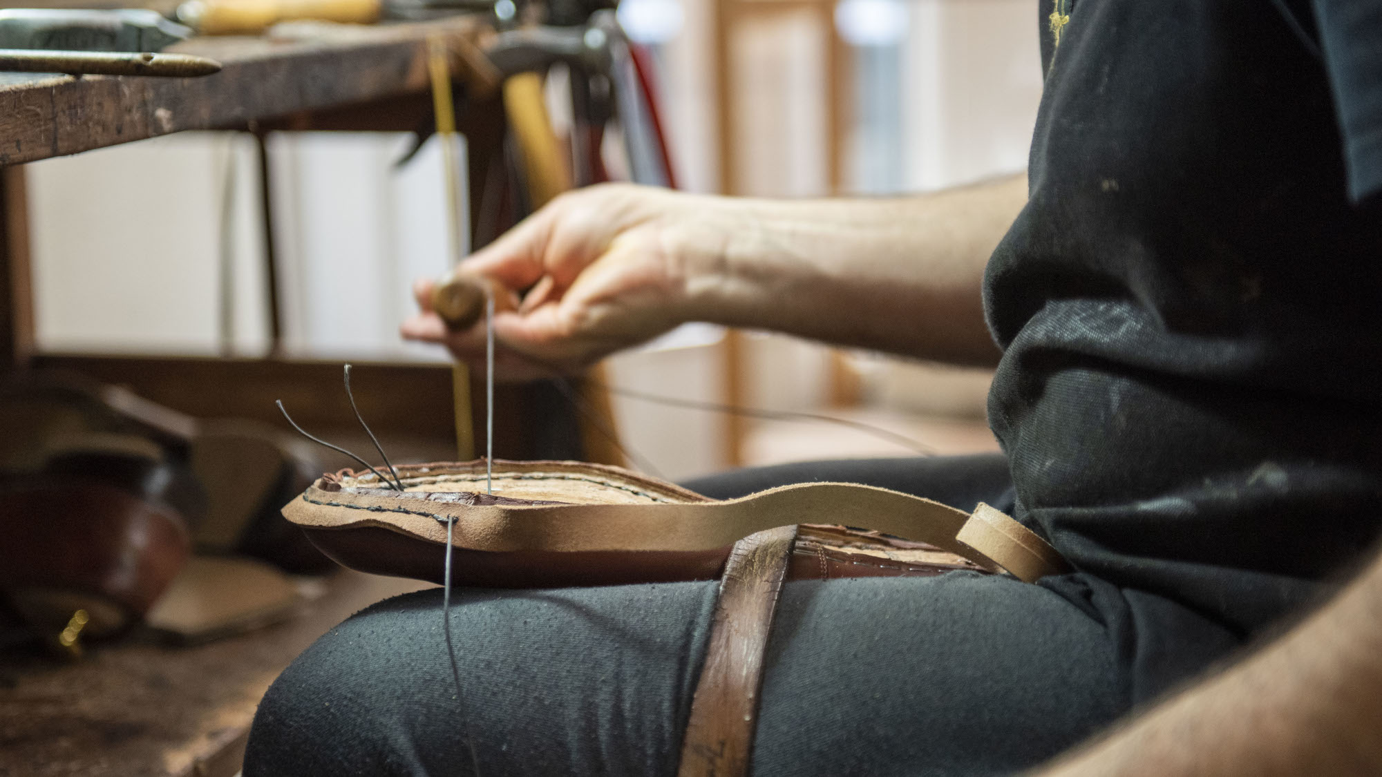 Mitarbeiter in Hamburger Maßschuhmacherei näht Schuh mit Pechdraht