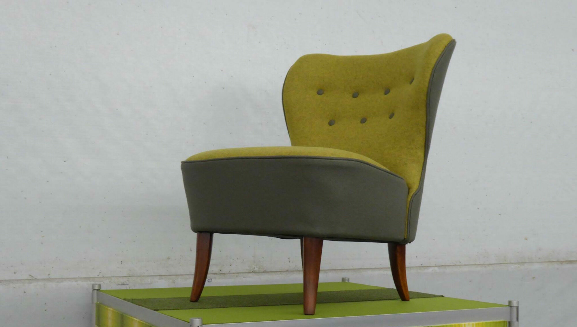 Ein grüner Cocktailsessel auf einem Podest