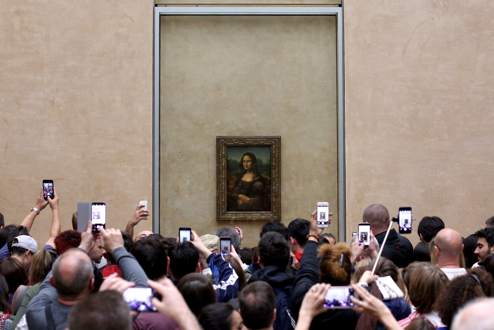 Zahlreiche Besucher fotografieren dicht gedrängelt das Gemälde der Mona Lisa im Museum mit ihren Smartphones Zahlreiche Besucher fotografieren dicht gedrängelt das Gemälde der Mona Lisa im Museum mit ihren Smartphones
