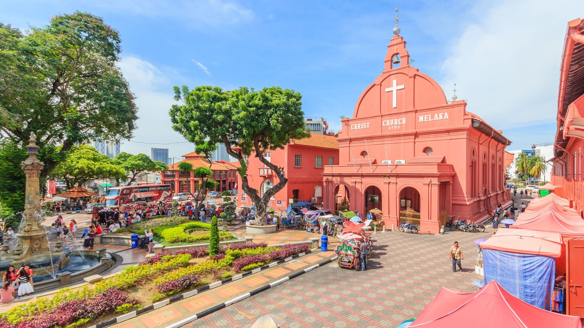 Belebter Platz mit Parkanlage, umgeben von pinkfarbenen Kolonialbauten samt Kirche unter blauem Himmel. Belebter Platz mit Parkanlage, umgeben von pinkfarbenen Kolonialbauten samt Kirche unter blauem Himmel.
