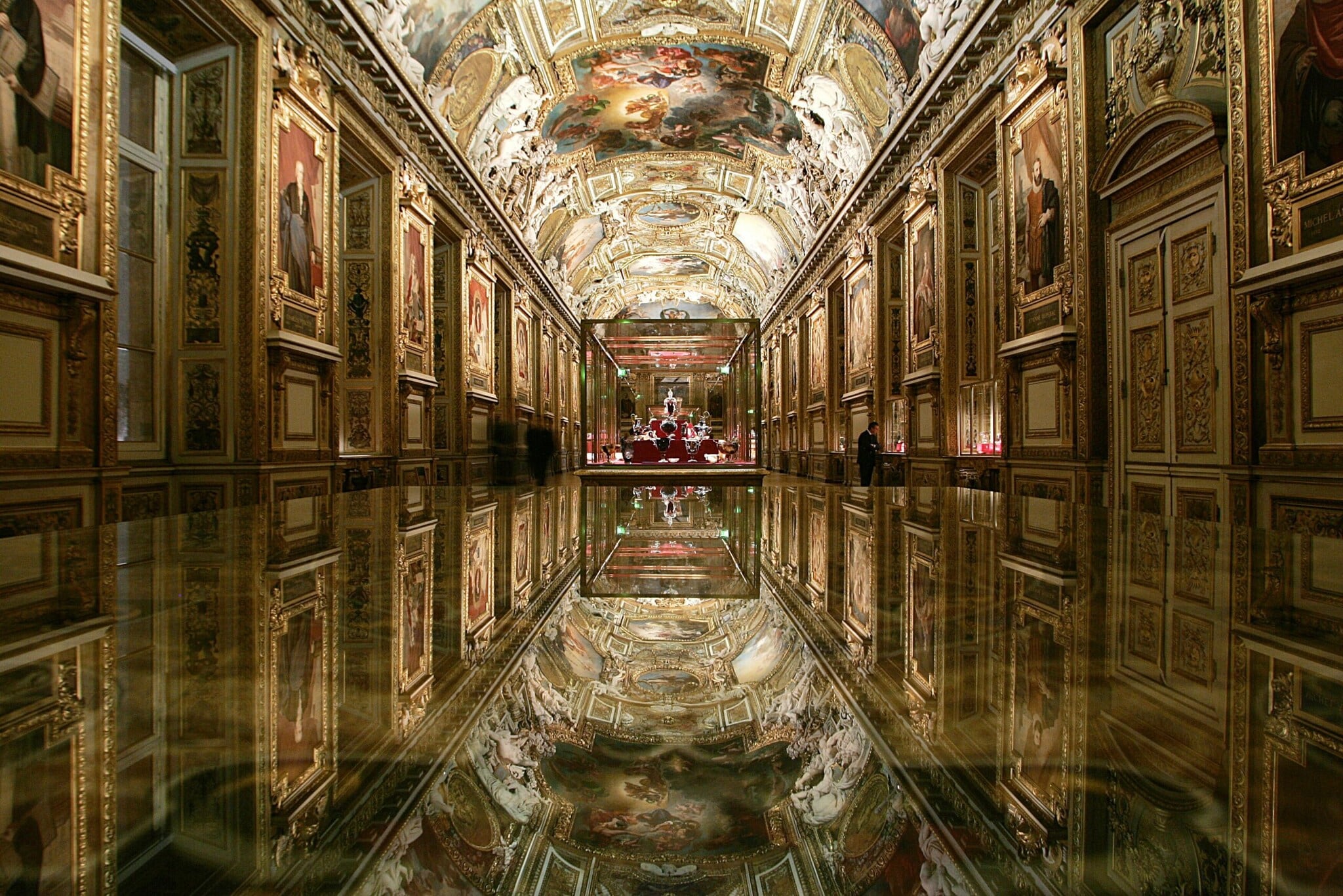 Innenaufnahme eines prunkvollen Saals im Louvre mit Ölgemälden und Fresko, im Zentrum eine Vitrine mit Schmuck Innenaufnahme eines prunkvollen Saals im Louvre mit Ölgemälden und Fresko, im Zentrum eine Vitrine mit Schmuck