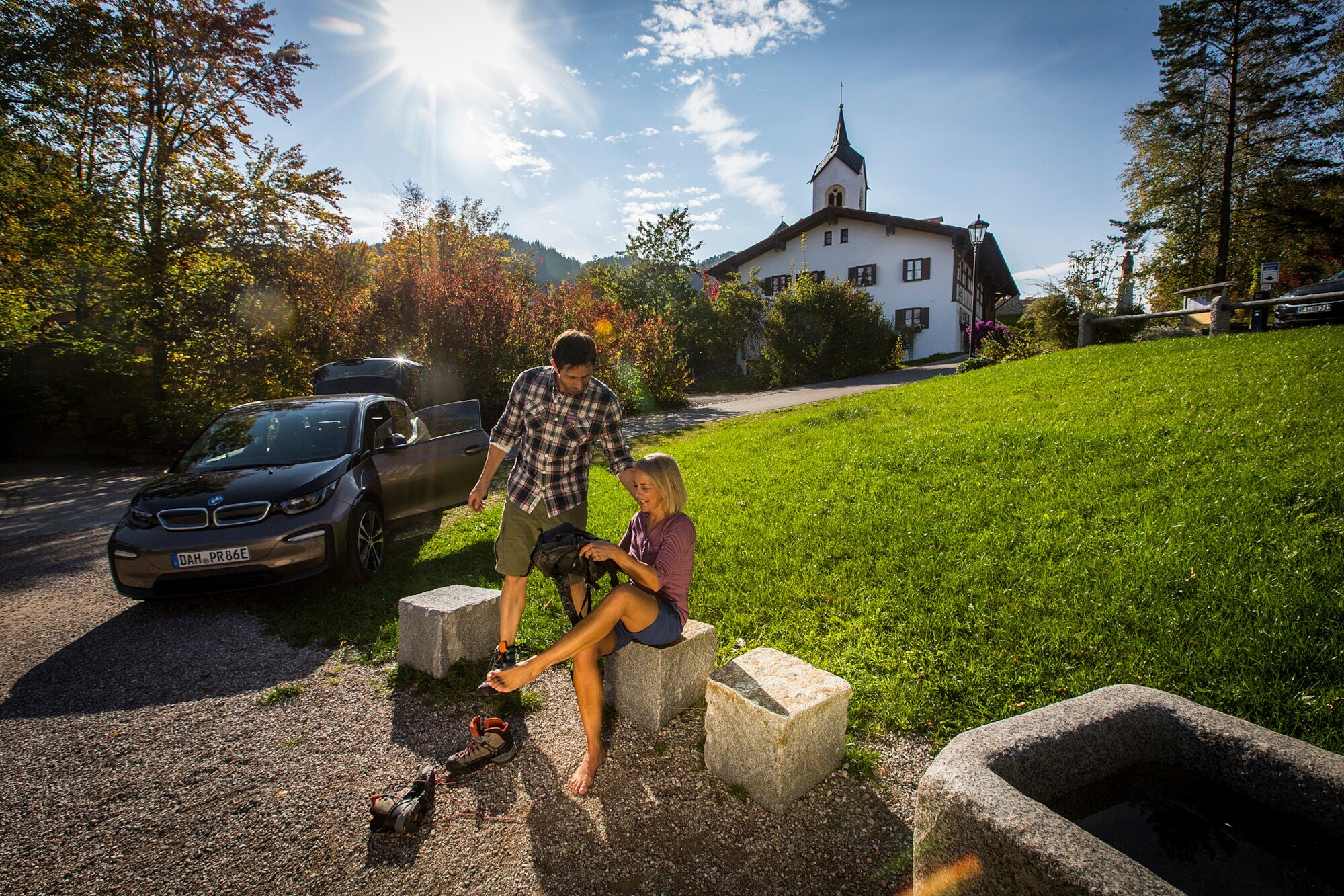 Ein Paar mit einem E-Auto vor einer malerischen Kirche