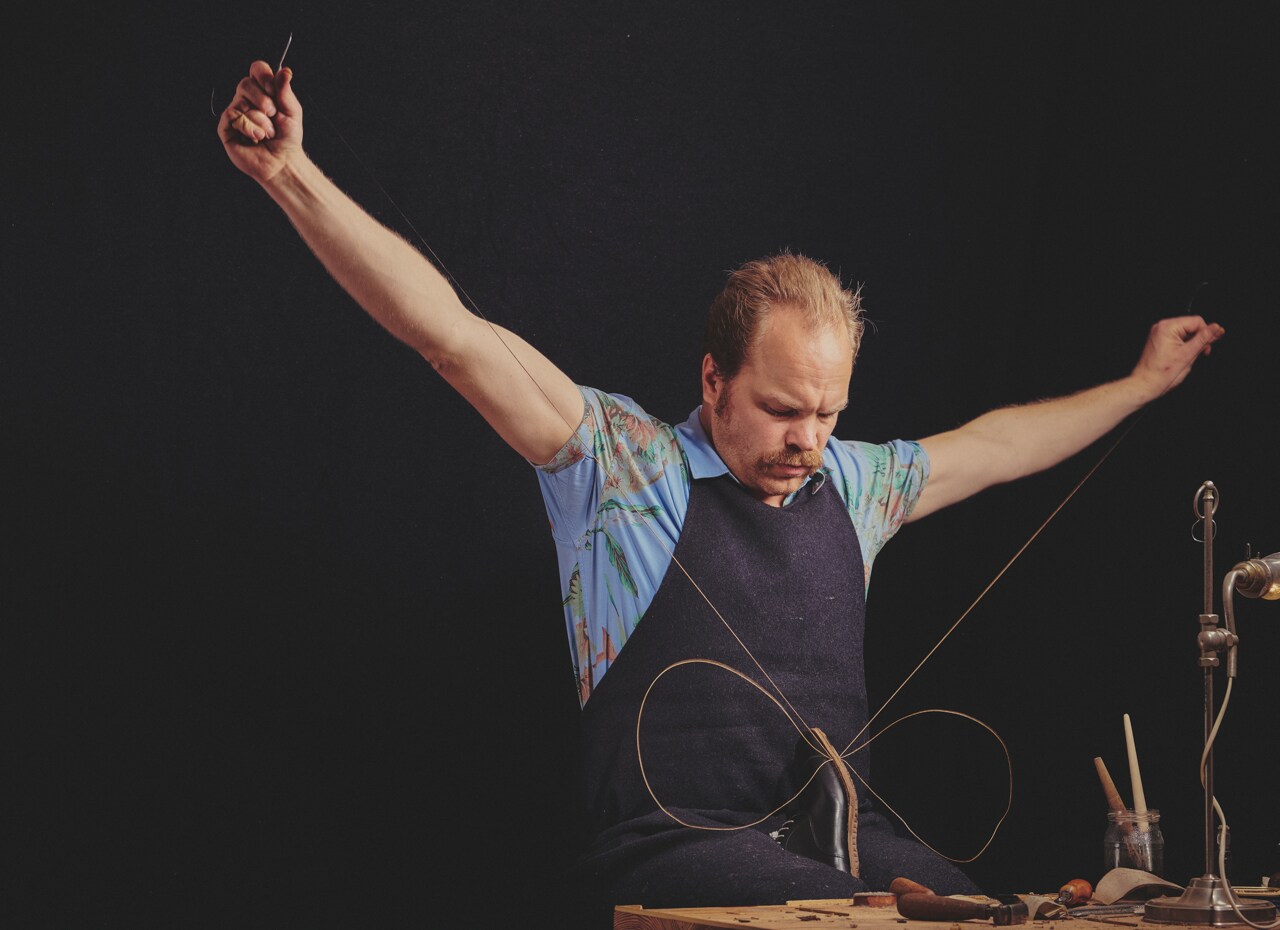 Korbinian Ludwig Heß zieht zwei Fäden durch einen Schuh