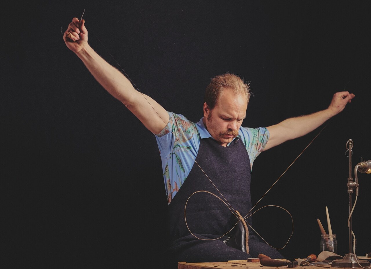 Korbinian Ludwig Heß zieht zwei Fäden durch einen Schuh Korbinian Ludwig Heß zieht zwei Fäden durch einen Schuh