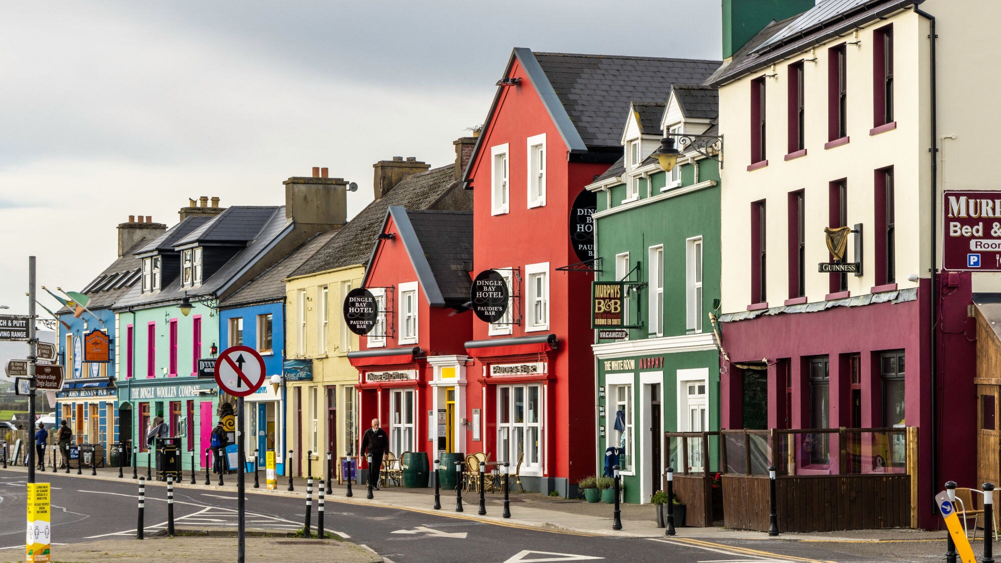 Bunte Häuserzeile mit roten, grünen und blauen Fassaden, Straßenszenen mit Verkehrsschildern und Laternen, irische Architektur. Bunte Häuserzeile mit roten, grünen und blauen Fassaden, Straßenszenen mit Verkehrsschildern und Laternen, irische Architektur.