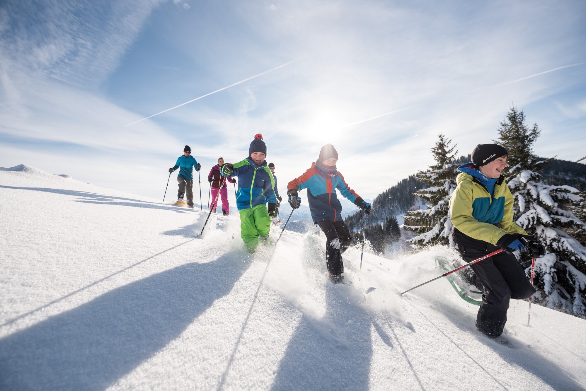 Kinder laufen mit Schneeschuhen bergab durch den Tiefschnee