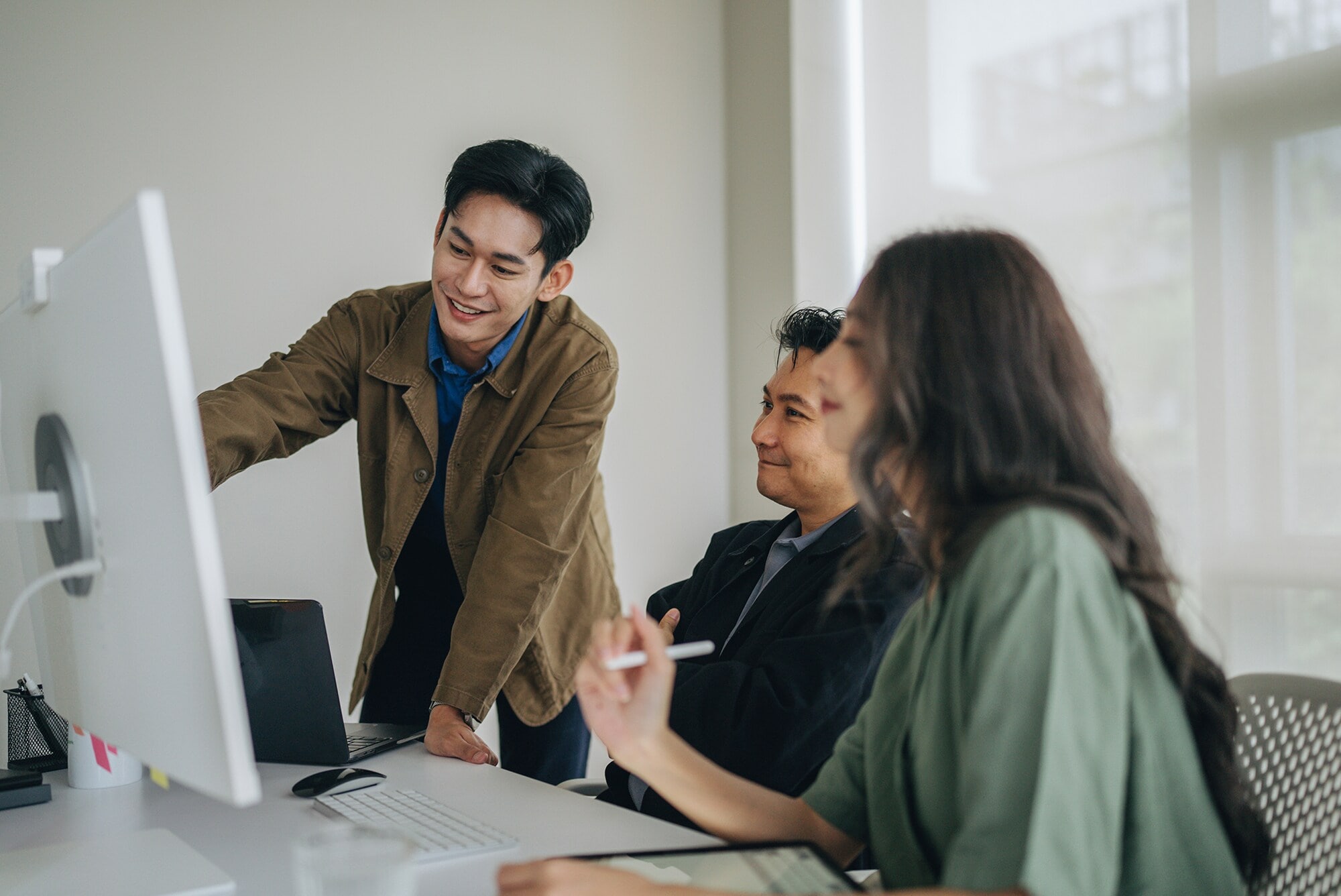 KI in der Buchhaltung: Längst keine Zukunftsmusik mehr Ein junger Mitarbeiter erklärt seinen Kolleg:innen etwas am Bildschirm.