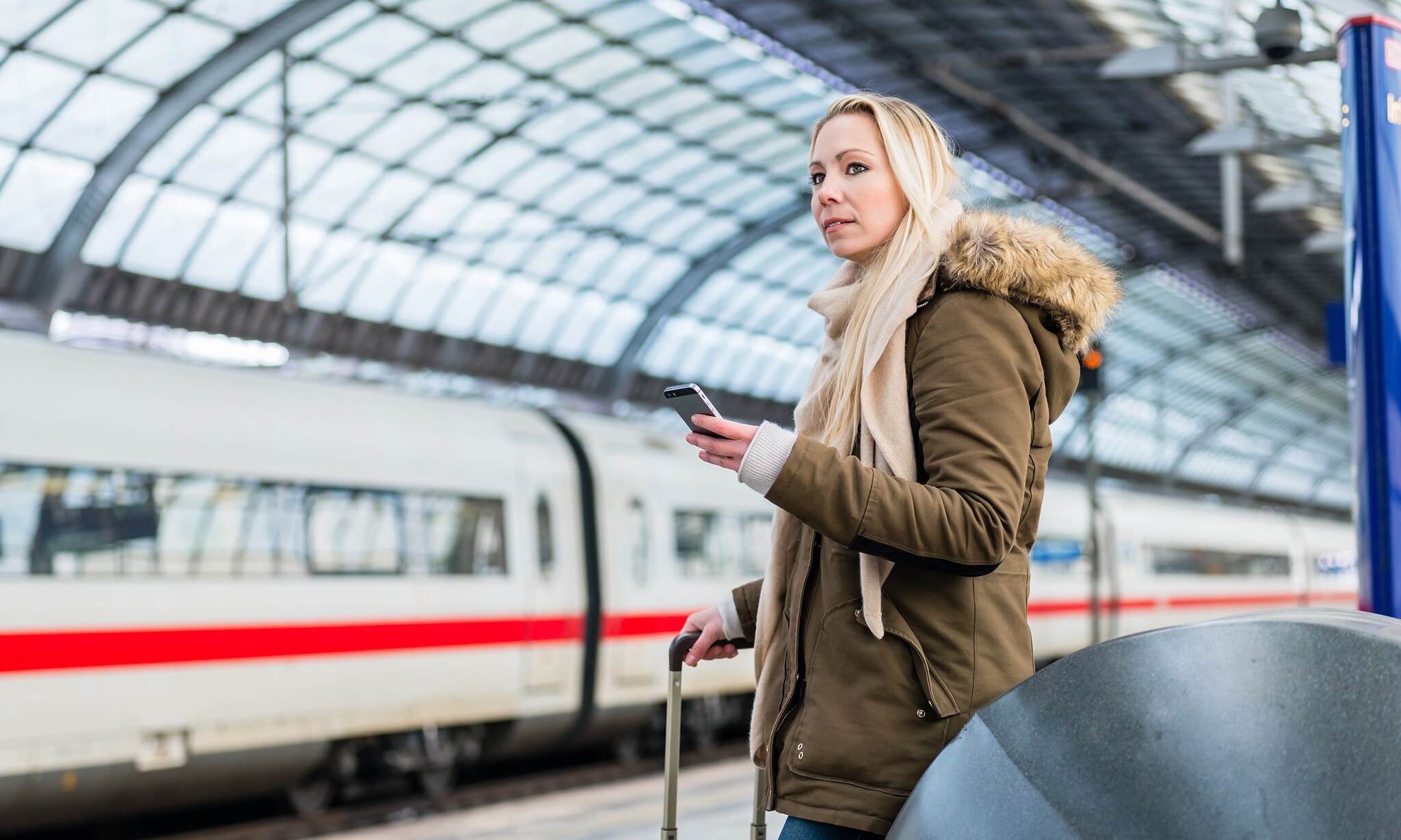 Woman in train station using time table app on phone