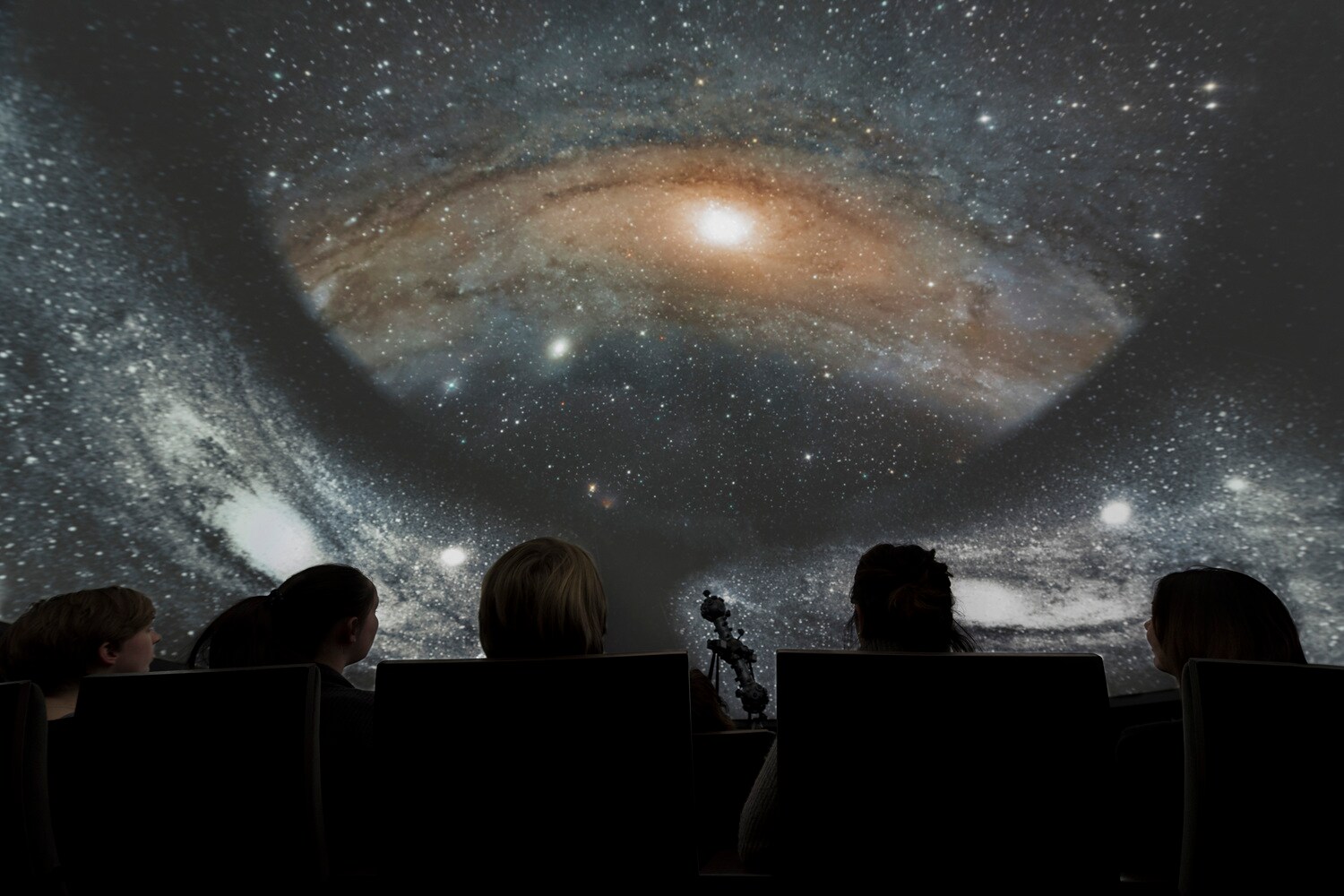 Zuschauer:innen im Planetarium, die in den Sternenhimmel schauen