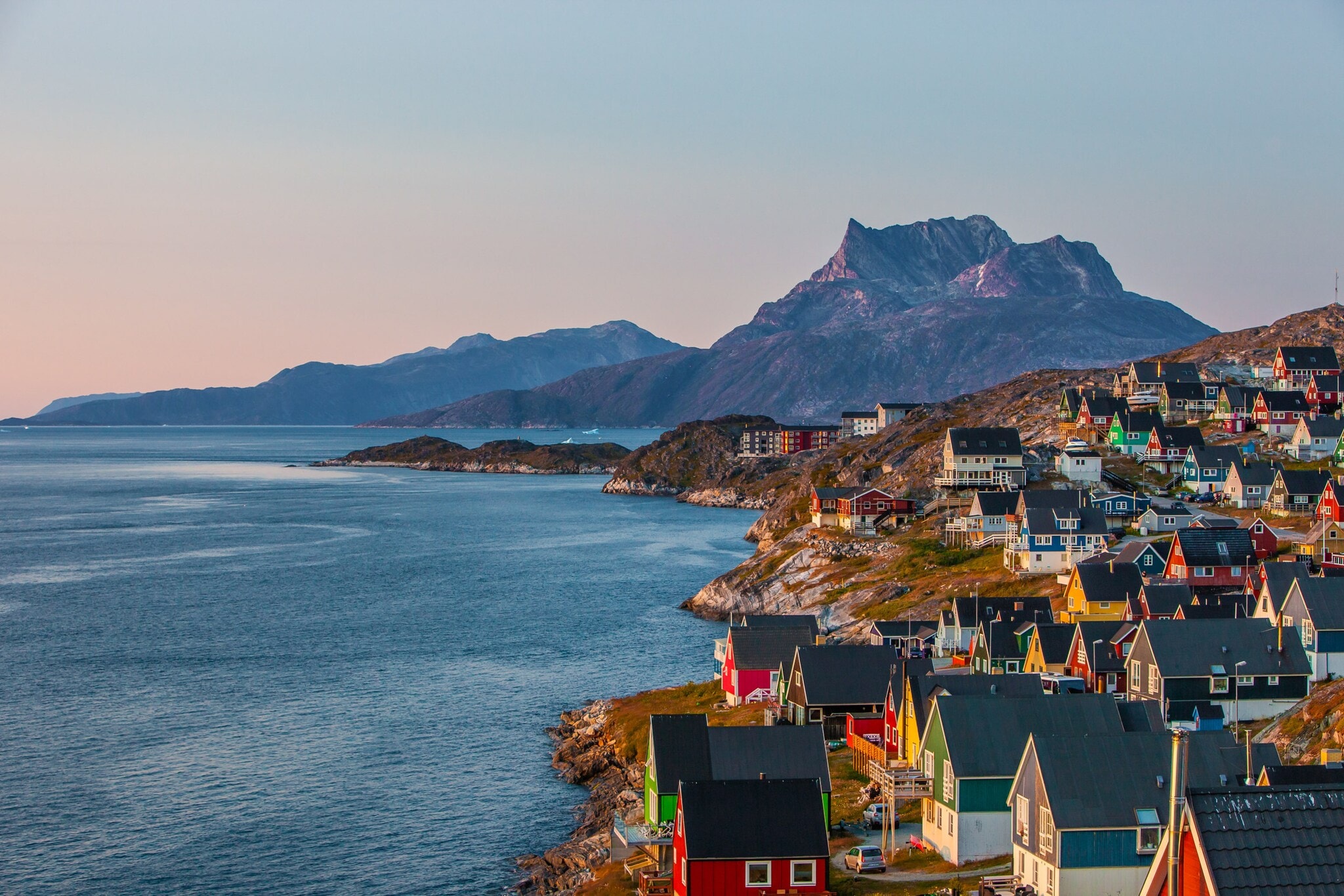 Bunte Häuser der grönländischen Hauptstadt Nuuk an einem Hang, der zum Wasser hin abfällt, im Hintergrund sind Berge. Bunte Häuser der grönländischen Hauptstadt Nuuk an einem Hang, der zum Wasser hin abfällt, im Hintergrund sind Berge.