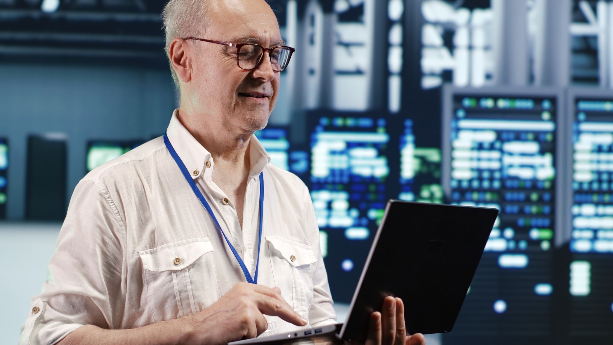 Ein Mann mit Brille ist in einem Rechenzentrum und schaut auf einen Laptop. Ein Mann mit Brille ist in einem Rechenzentrum und schaut auf einen Laptop.