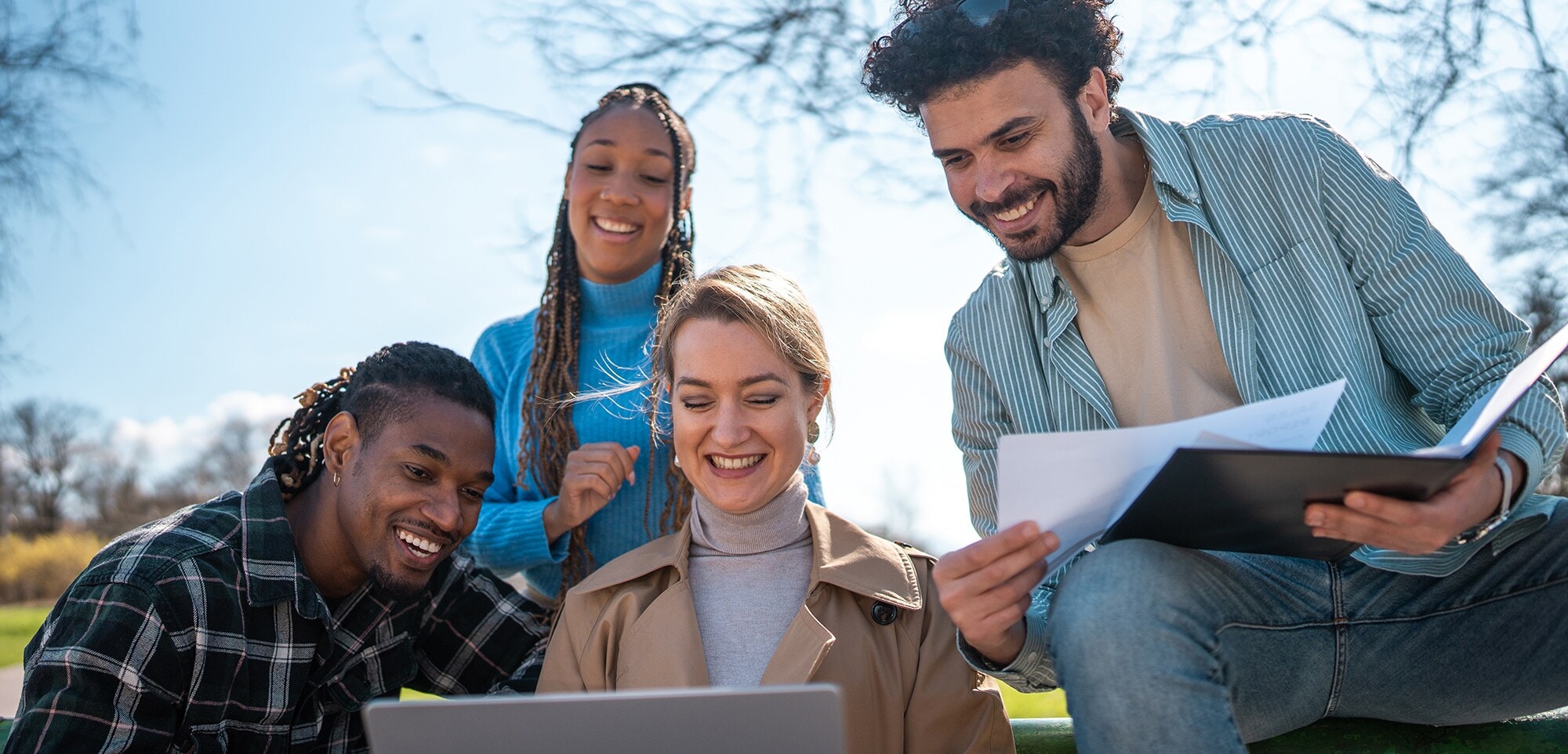4 junge Geschäftsleute bei einem Meeting draußen im Park