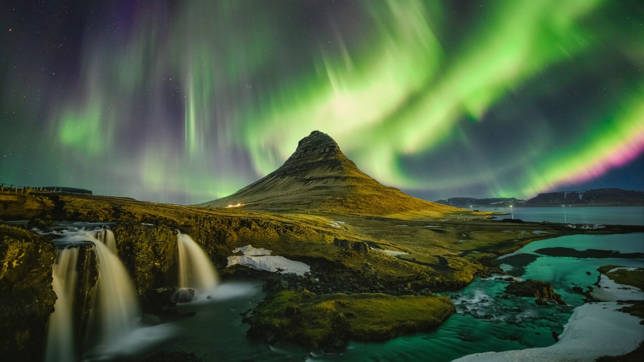 Moosbedeckte Vulkanlandschaft mit Wasserfällen unter Nachthimmel mit grün und lila leuchtenden Polarlichtern. Moosbedeckte Vulkanlandschaft mit Wasserfällen unter Nachthimmel mit grün und lila leuchtenden Polarlichtern.