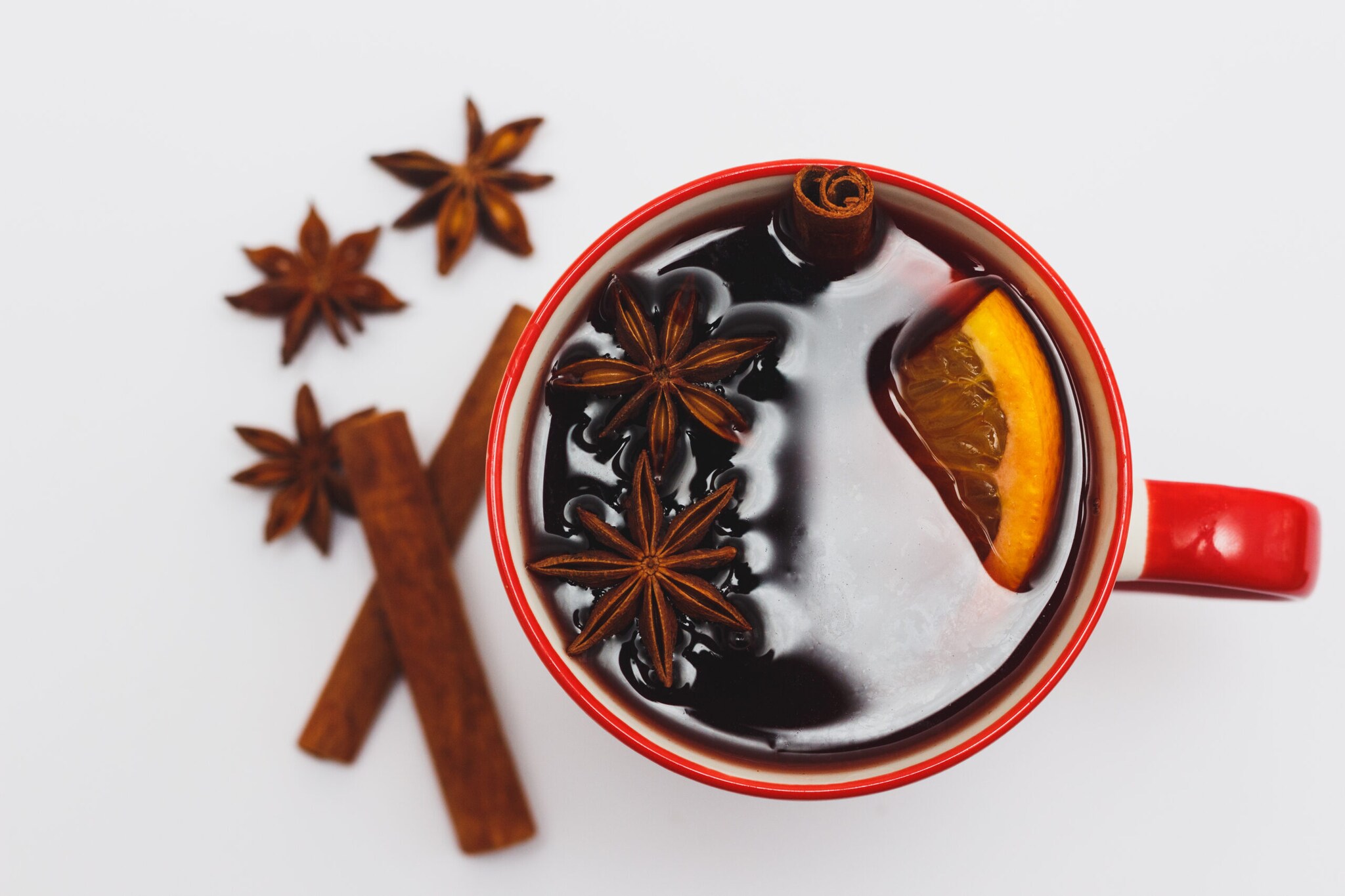 Glühbier mit Saft, Orange, Zitrone, Zimt und Sternanis in einer roten Tasse