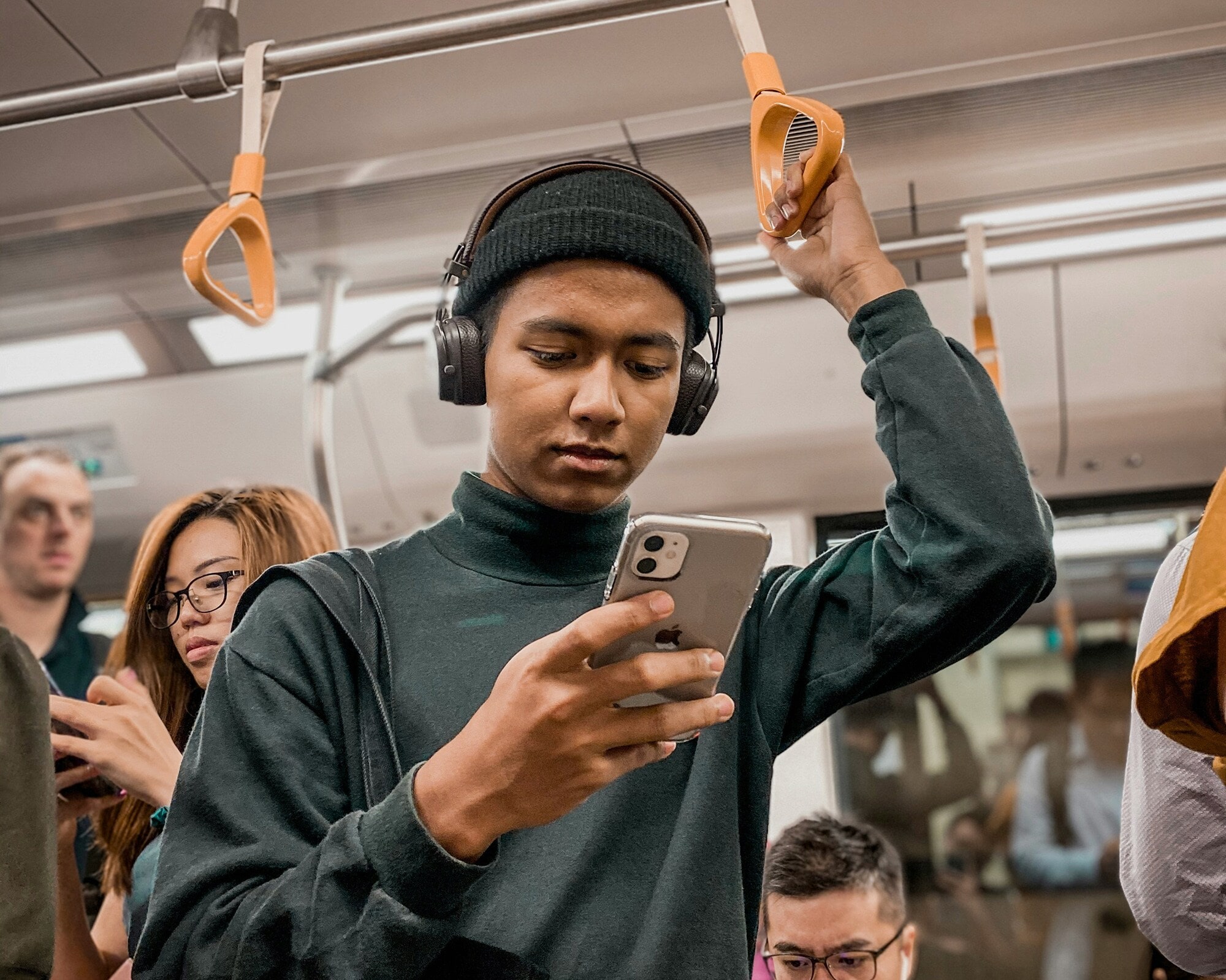 Social-Recruiting-Agentur Adstark: im Gespräch mit Ruslan Ilyassov Ein junger Mann in der U-Bahn liest auf seinem Smartphone.