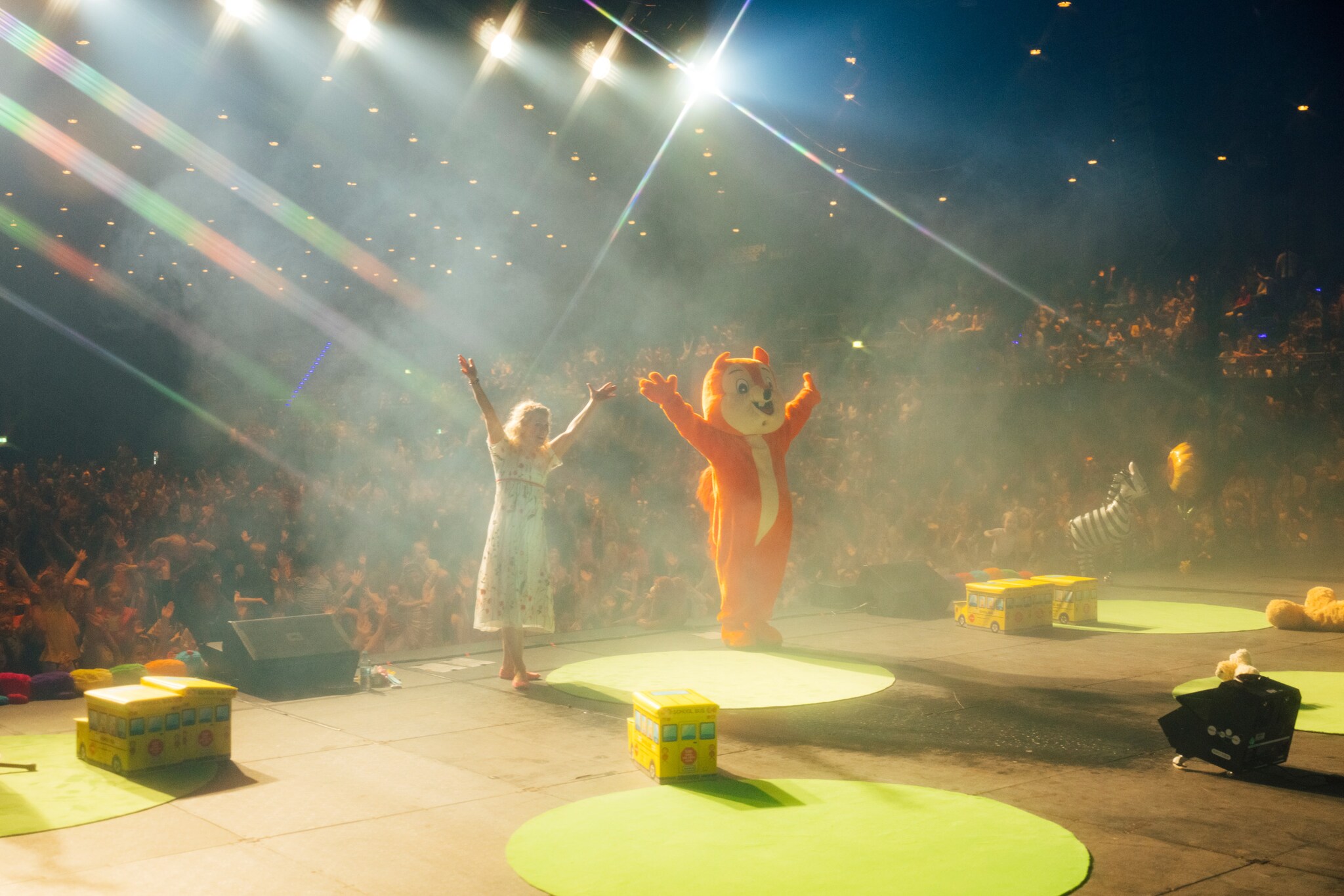 Simone Sommerland und eine Person im Eichhörnchen-Kostüm stehen mit weit ausgebreiteten Armen auf der Bühne mit dem Rücken zum Publikum. Simone Sommerland und eine Person im Eichhörnchen-Kostüm stehen mit weit ausgebreiteten Armen auf der Bühne mit dem Rücken zum Publikum.