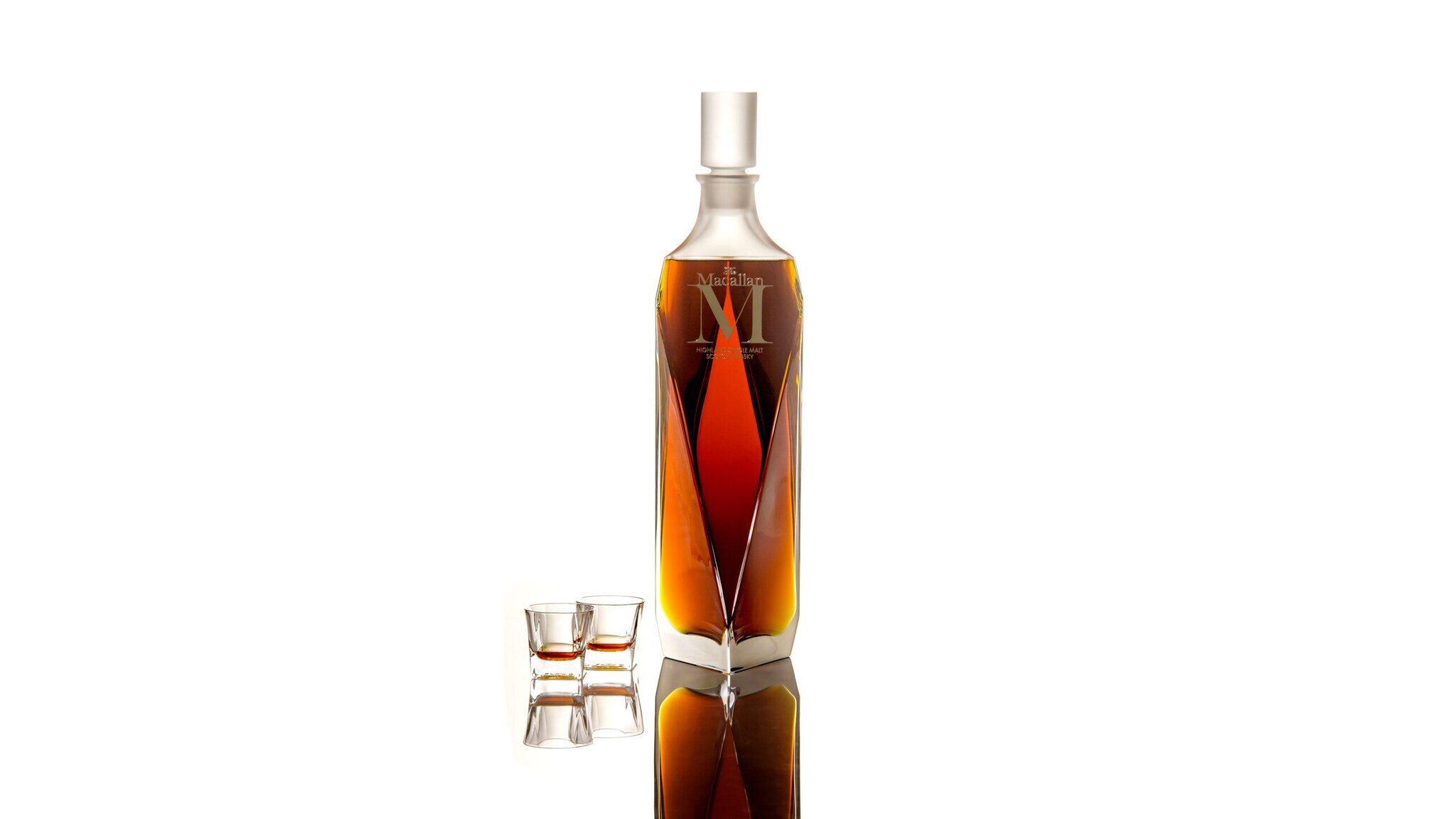 In Diamantenform geschliffener Dekanter mit Whisky der Marke Macallan M, daneben zwei kleine Whisky-Gläser