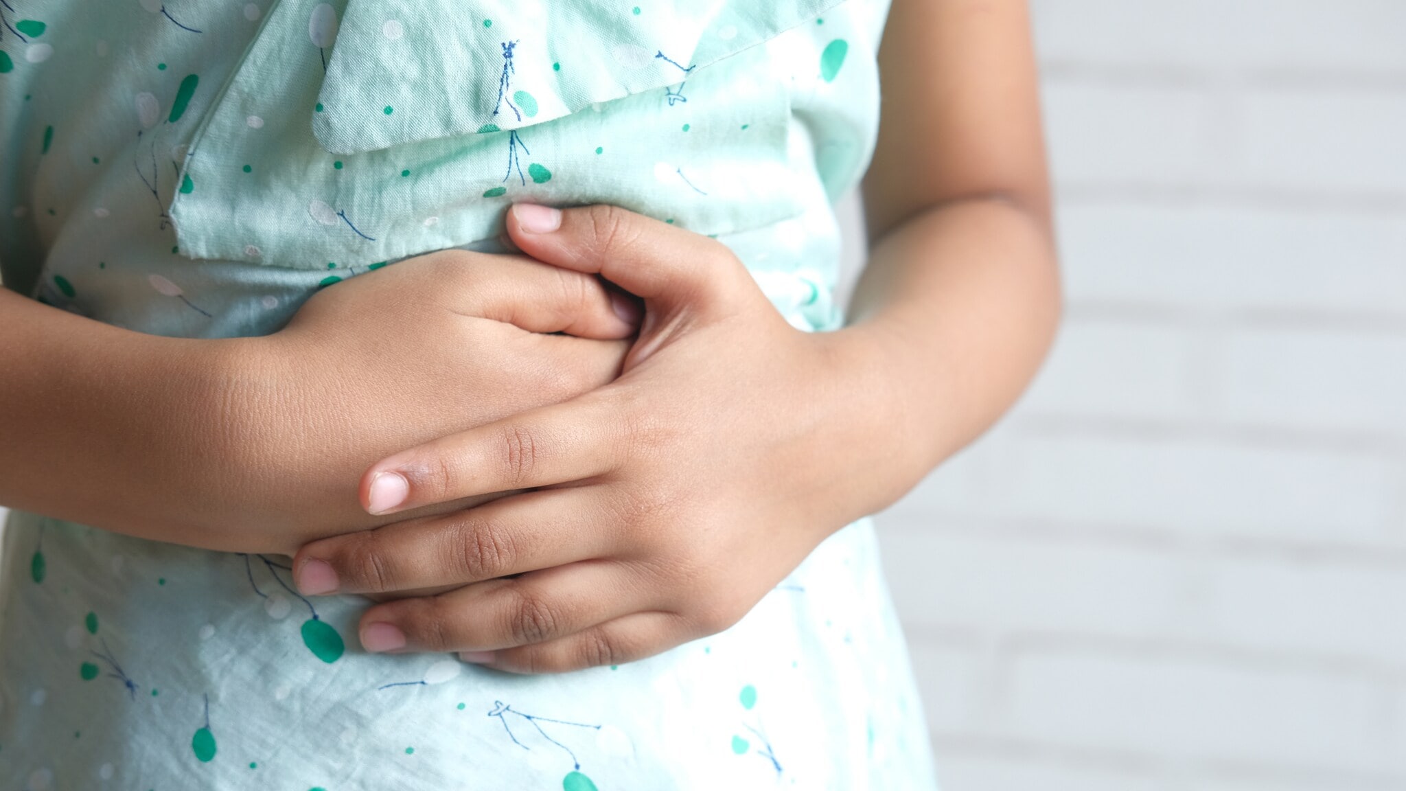 Ein Kind hält mit beiden Händen den Bauch. Ein Kind hält mit beiden Händen den Bauch.