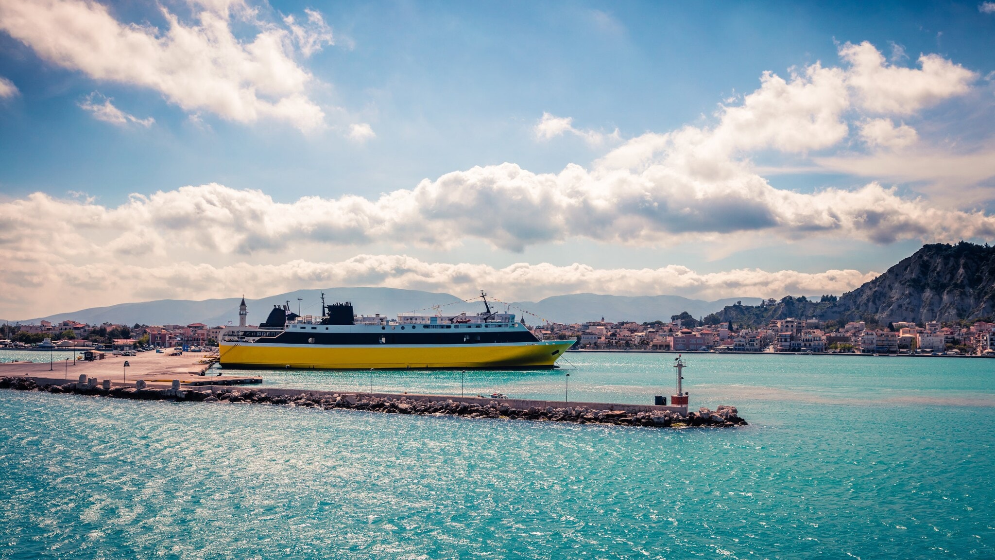 Fähre am Hafen mit Stadt und Bergen im Hintergrund unter bewölktem Himmel Fähre am Hafen mit Stadt und Bergen im Hintergrund unter bewölktem Himmel