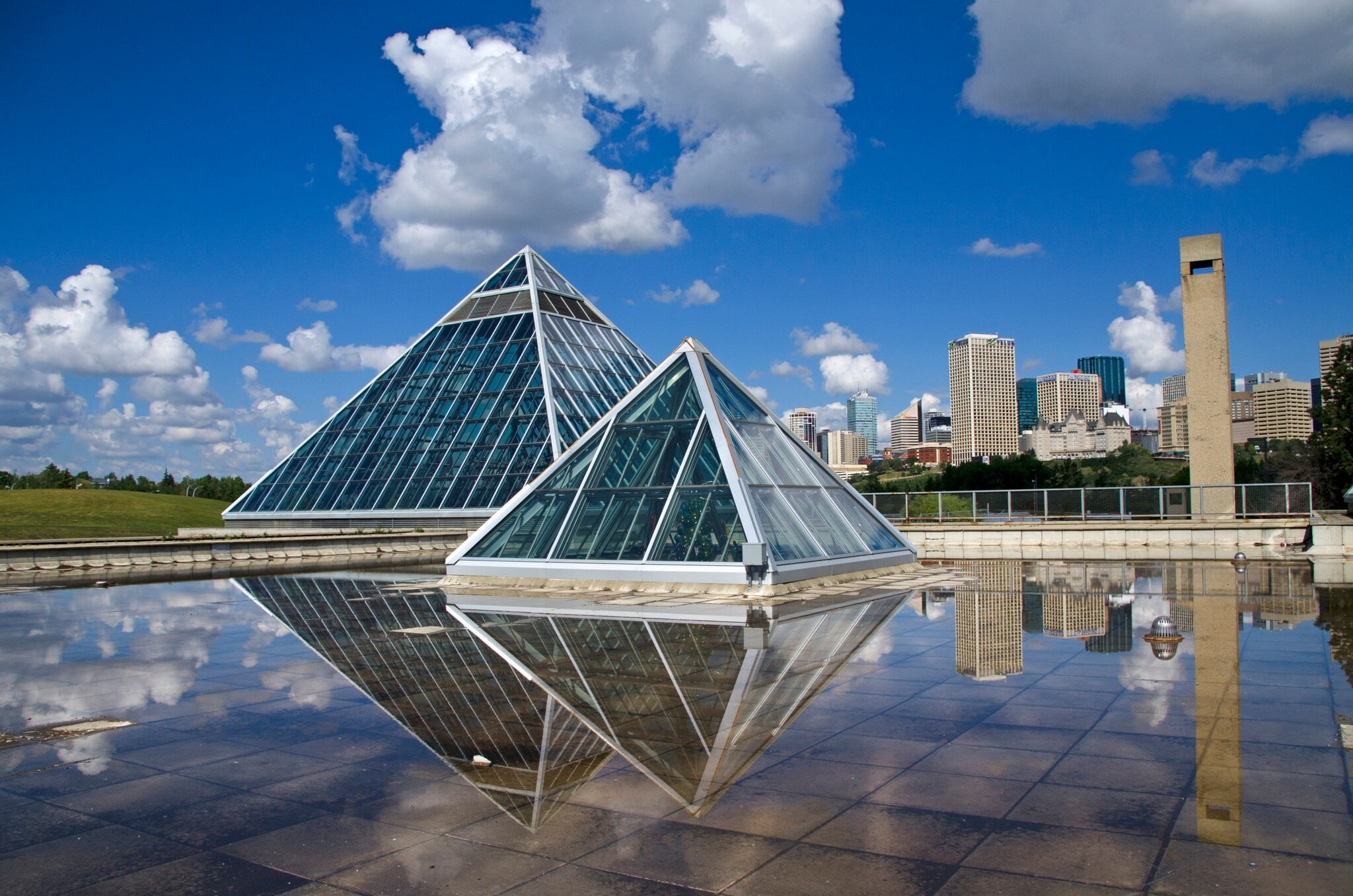 Zwei gläserne Pyramiden des Muttart Conservatory, umgeben von Grün und Wasser. Zwei gläserne Pyramiden des Muttart Conservatory, umgeben von Grün und Wasser.