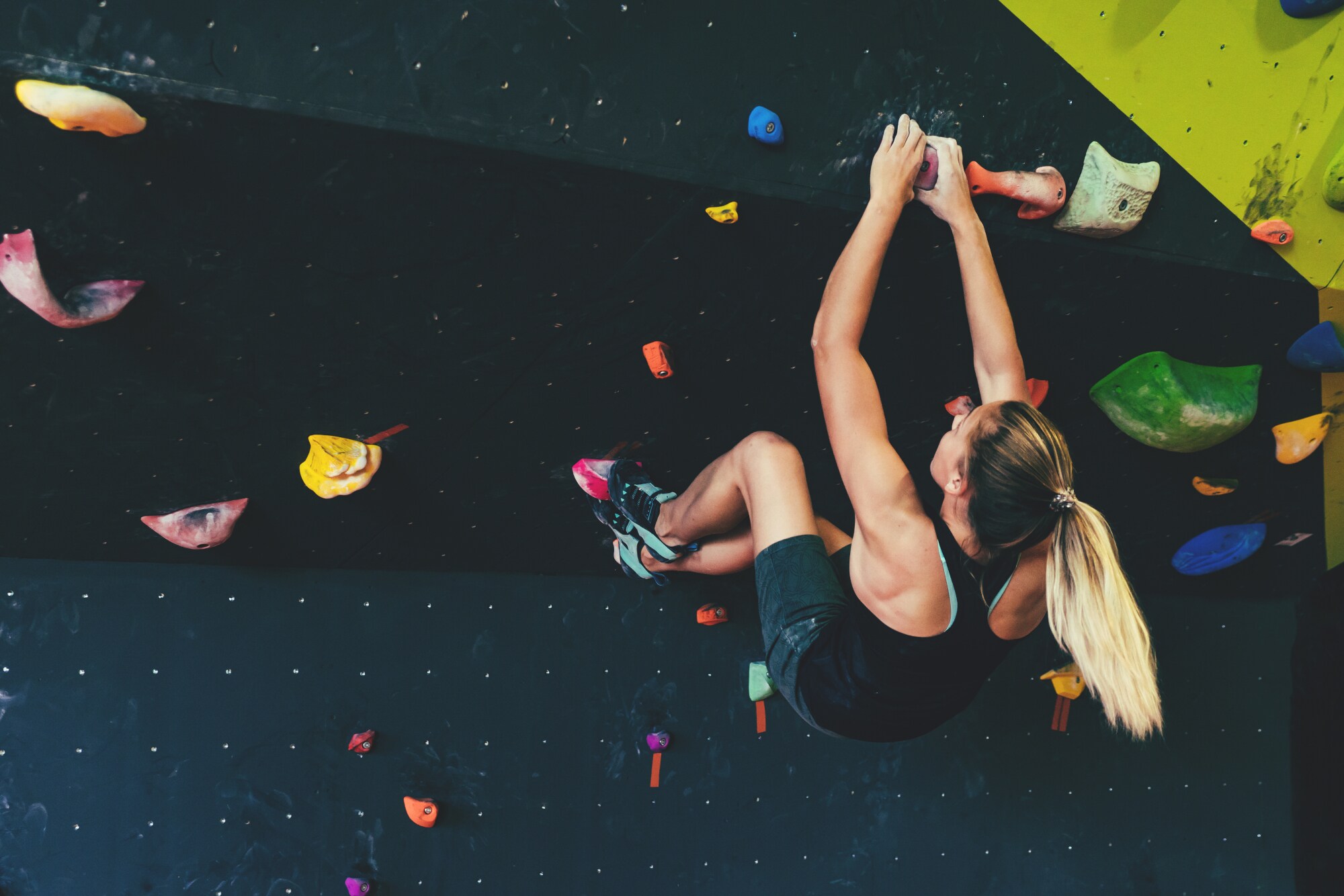 Kletterin an einer Kletterwand in einer Halle