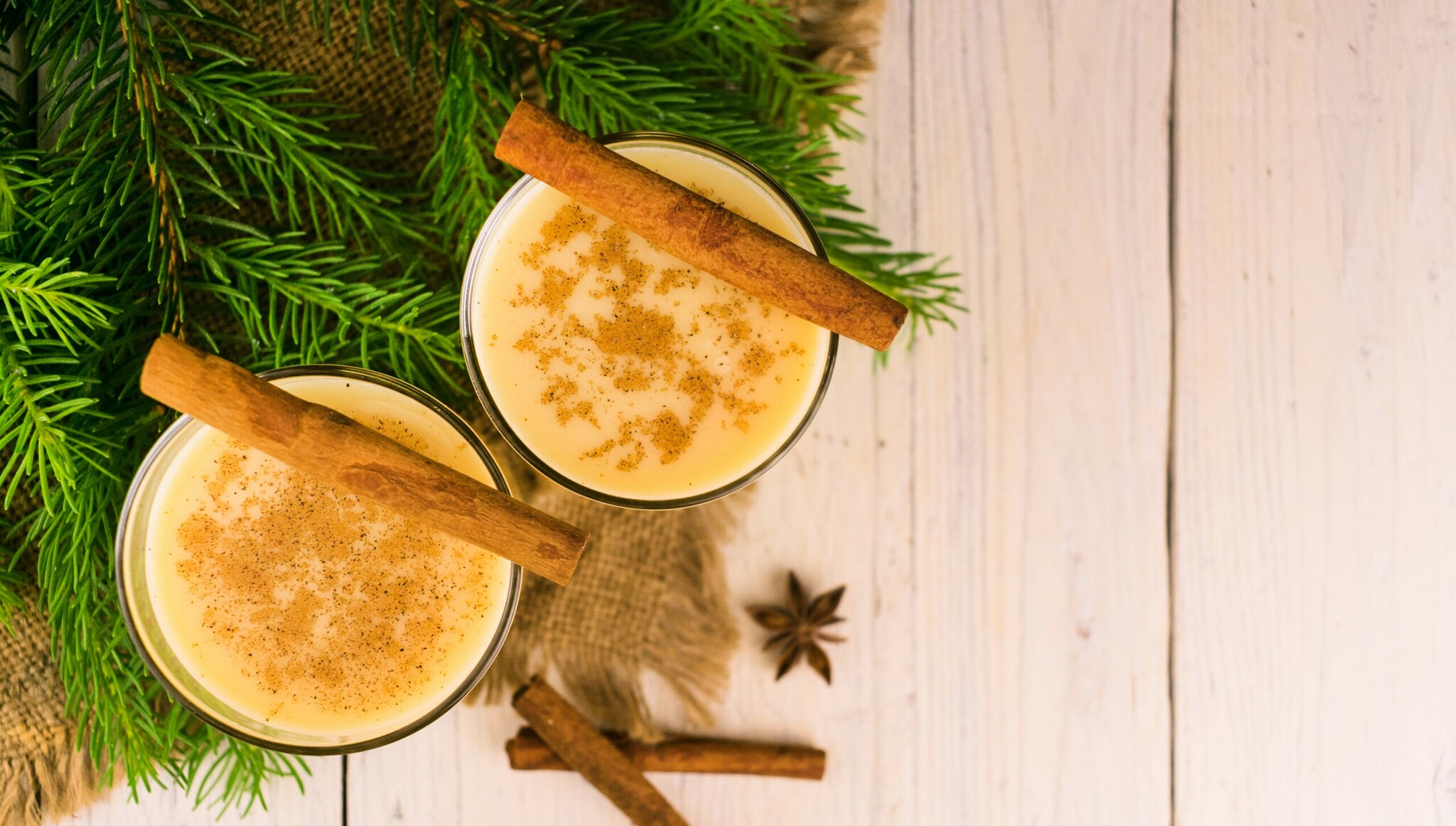 Zwei Gläser mit Glüh-Kaffee mit viel Milch und weihnachtlichen Gewürzen wie Zimtstangen und Anissternen Zwei Gläser mit Glüh-Kaffee mit viel Milch und weihnachtlichen Gewürzen wie Zimtstangen und Anissternen