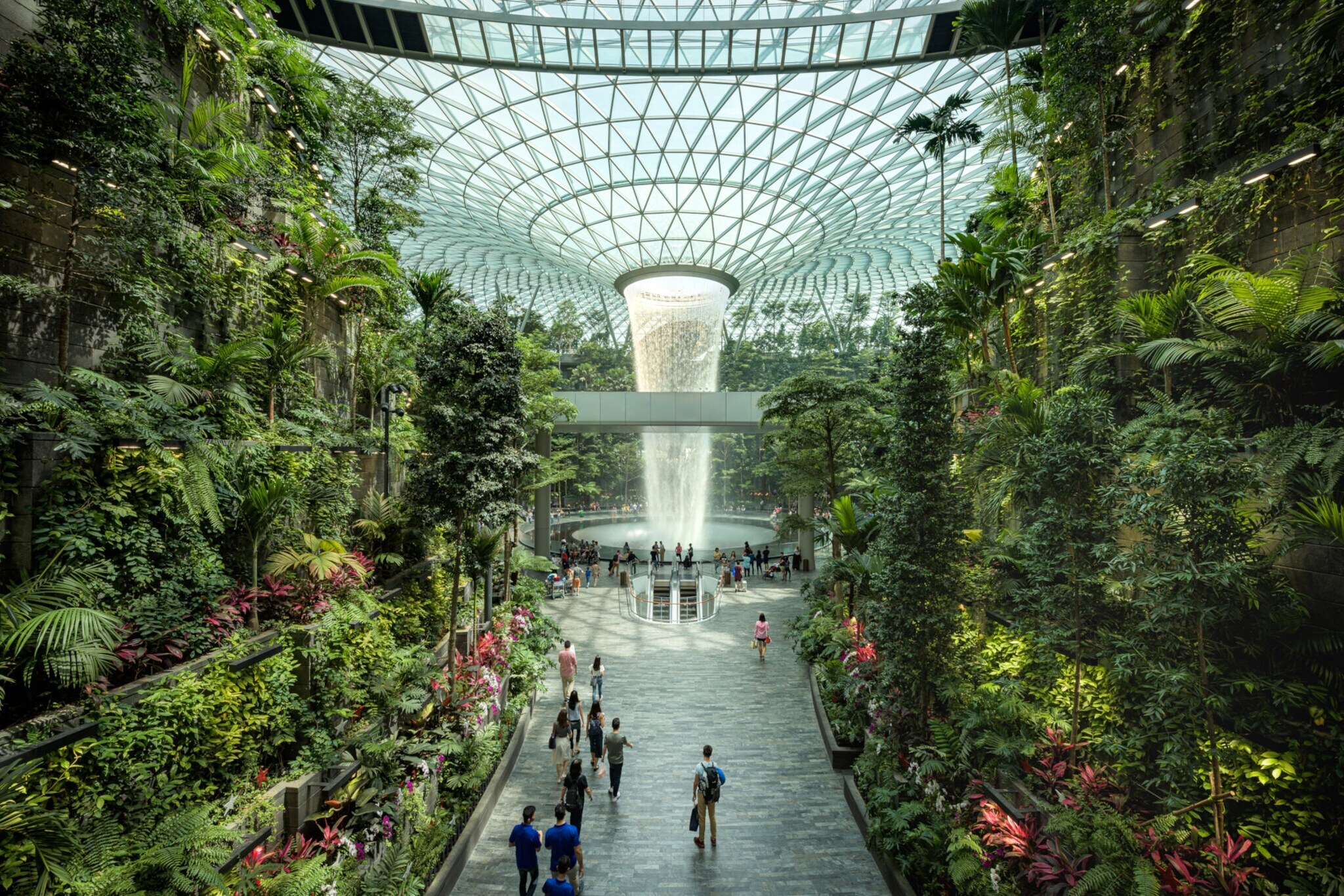Personen an einem Wasserfall in einem vertikalen Garten in einem Flughafenterminal.