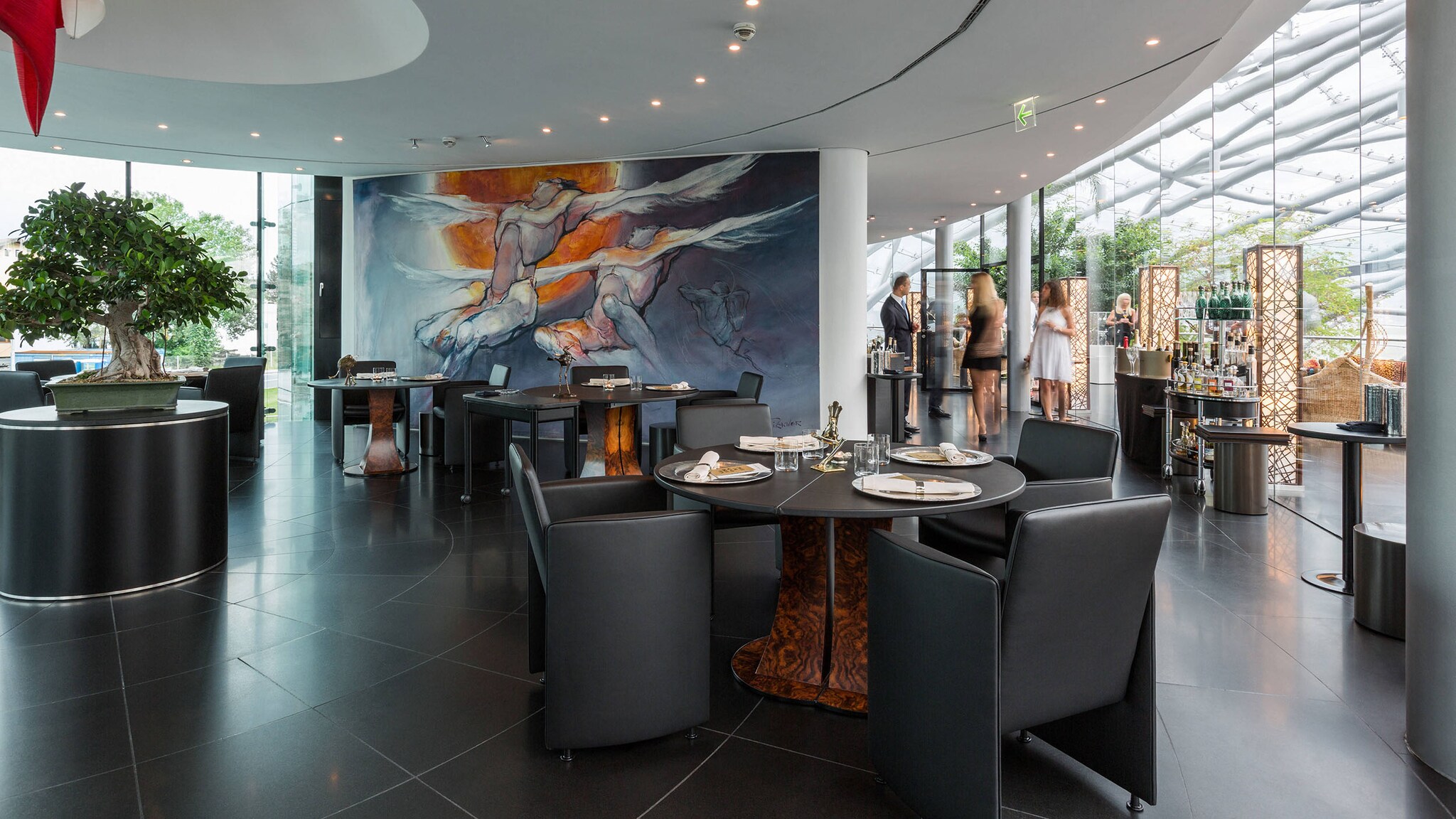 Stehende Personen in einem modernen Restaurant in einem lichtdurchfluteten Gebäude mit Glaskuppel.