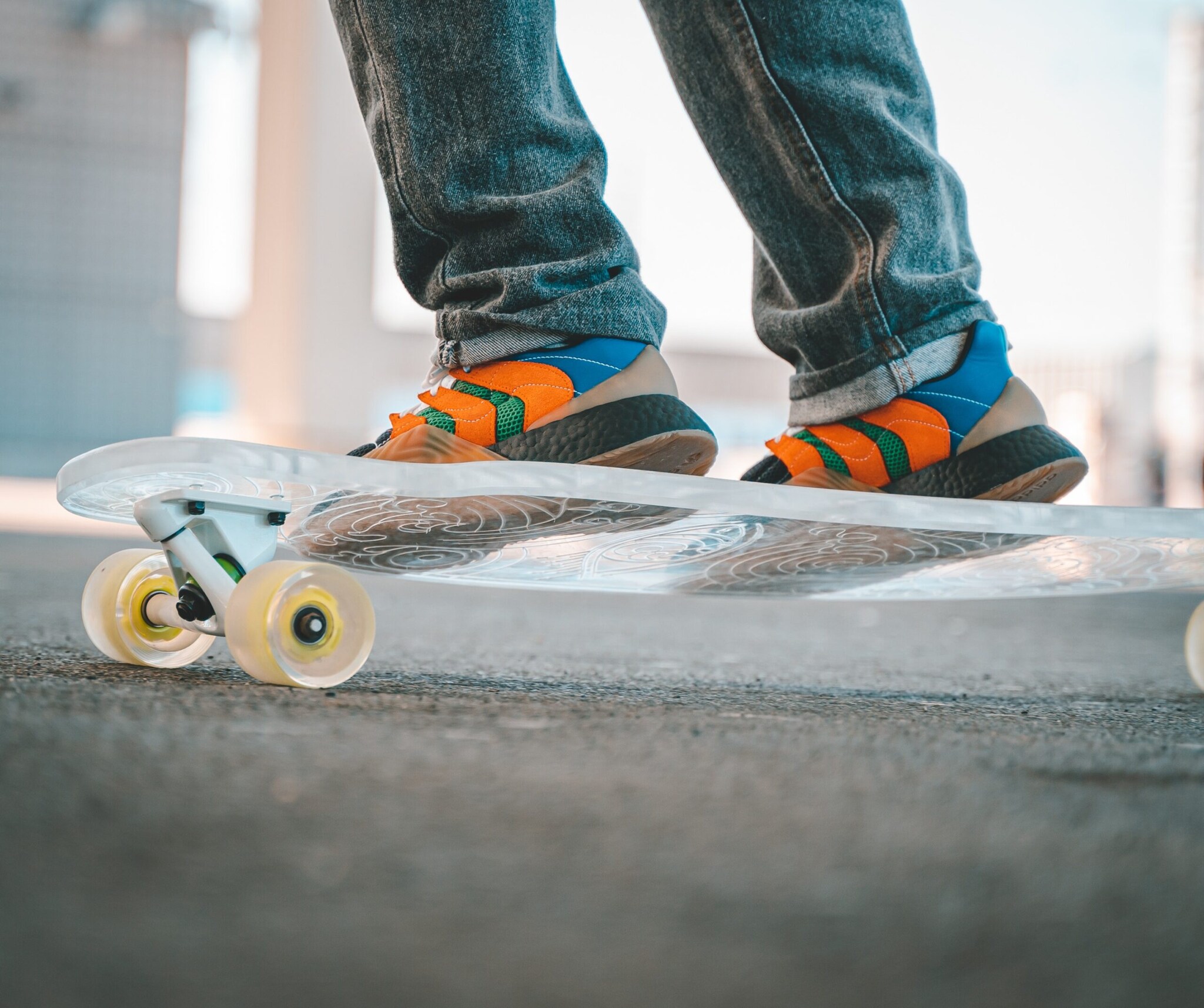 Ein graviertes, durchsichtiges Longboard, darauf ein Paar Füße in Turnschuhen