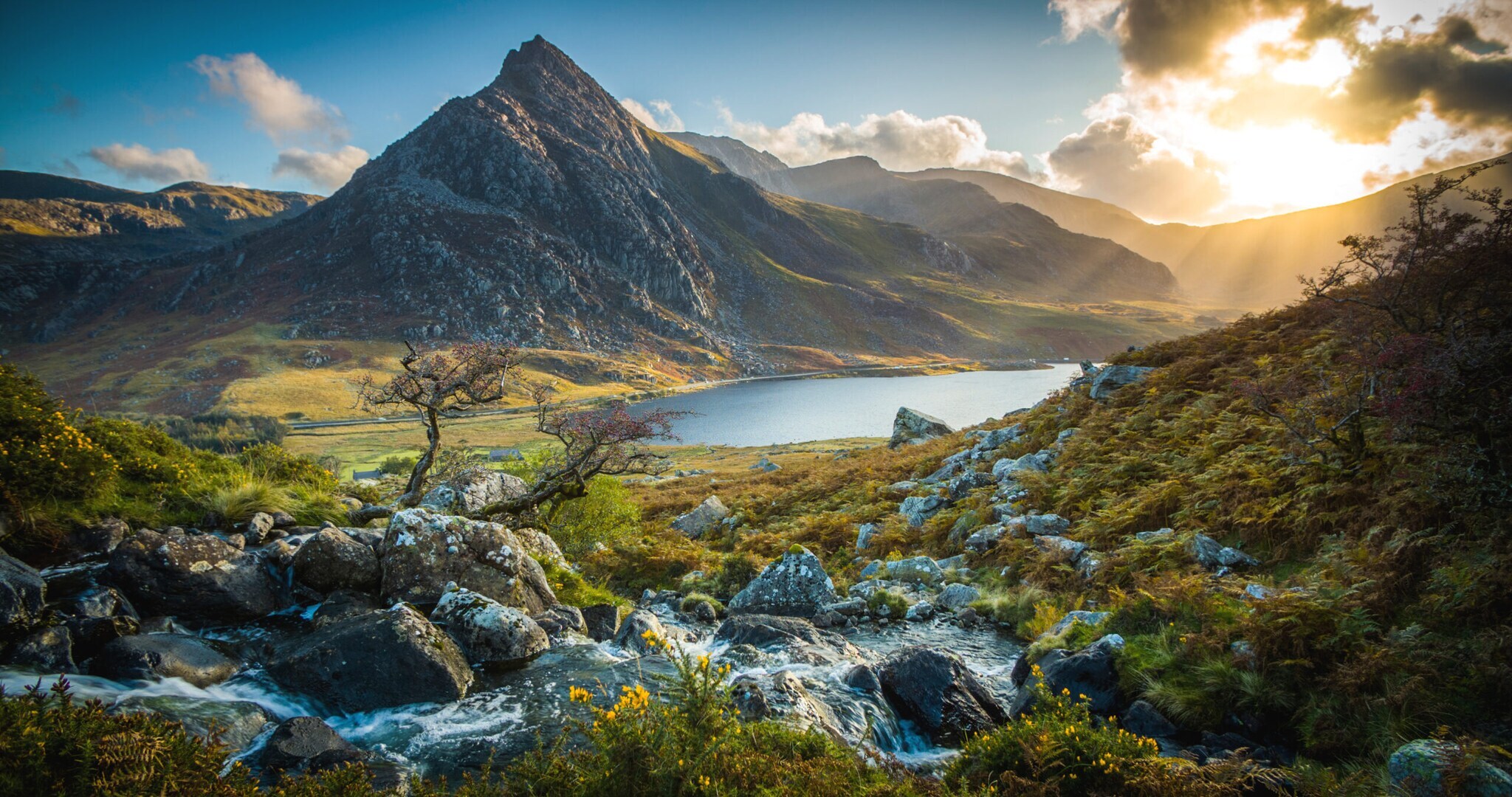 Landschaftspanorama mit Bergsee, umgeben von schroffen Felsen und wilder Natur.