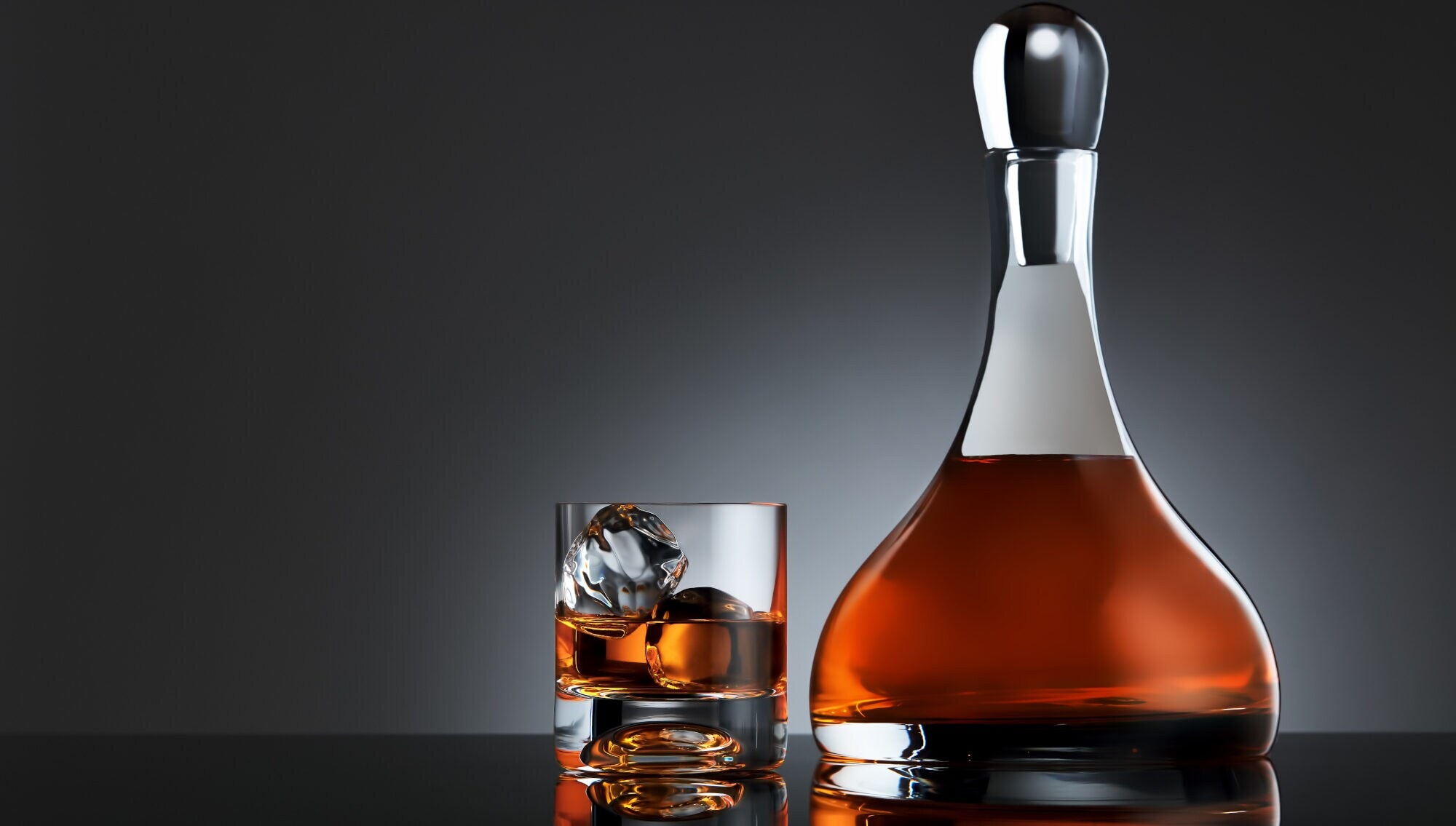 Ein Glas mit Whisky und Eiswürfeln neben einer Karaffe mit Whisky