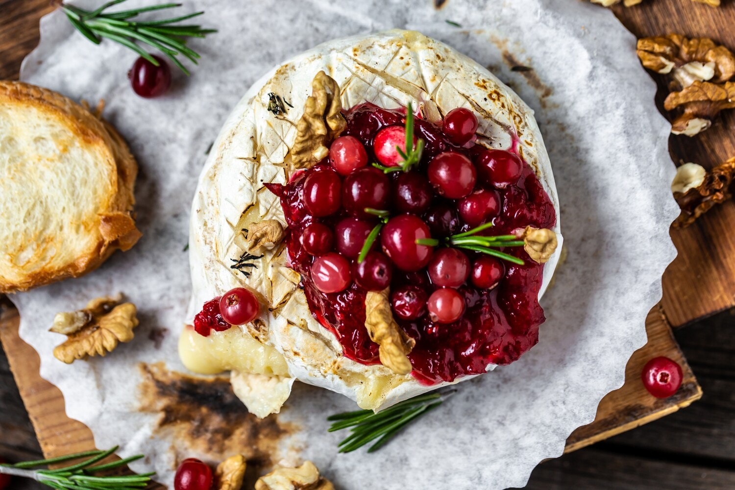 Traditioneller französischer gebackener Camembert mit Preiselbeeren und Nüssen angerichtet, garniert mit Rosmarin und Baguettebrot Traditioneller französischer gebackener Camembert mit Preiselbeeren und Nüssen angerichtet, garniert mit Rosmarin und Baguettebrot