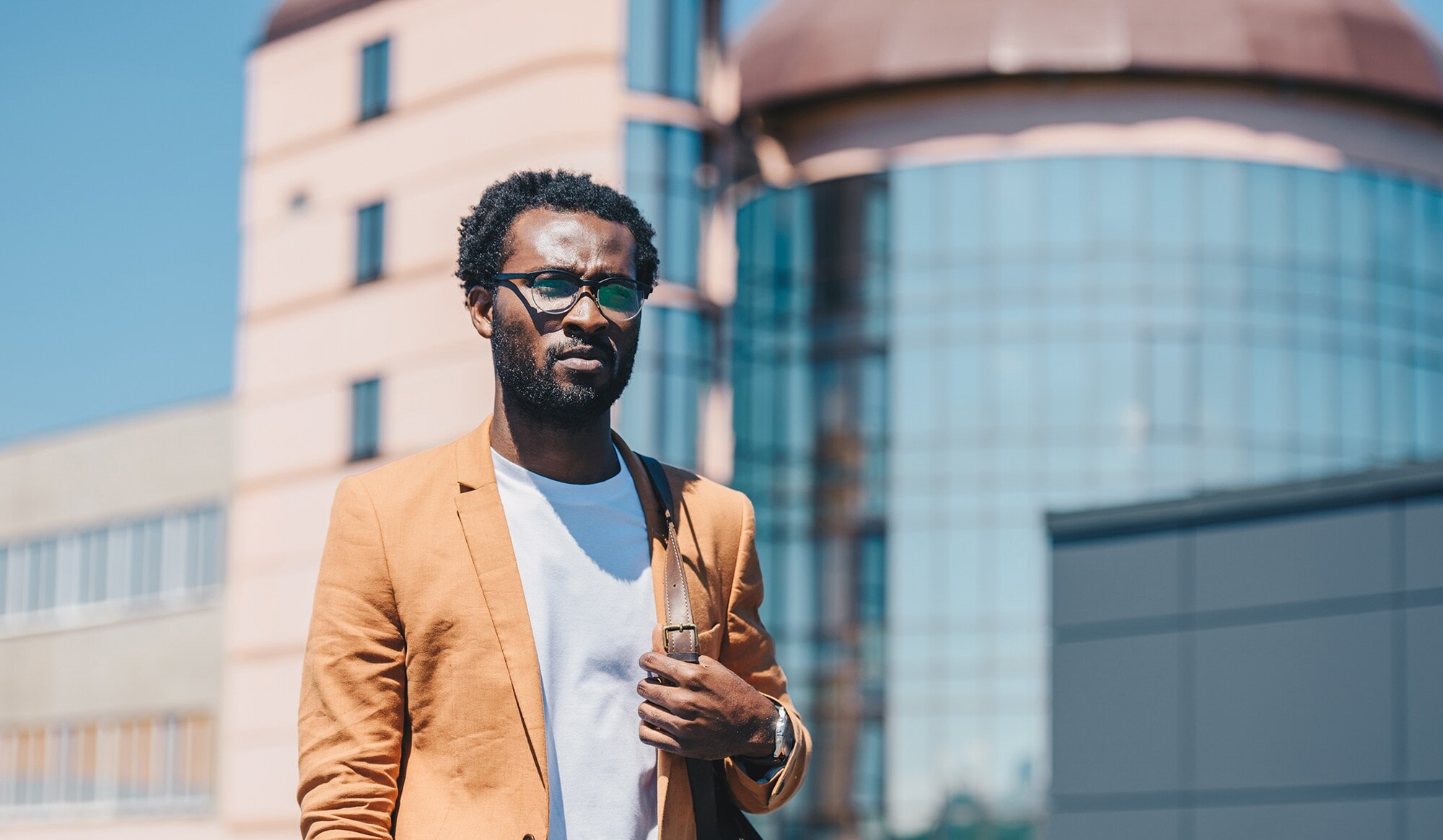 Business-Look im Sommer: So kommst du stylish durch die Hitzewelle Geschäftsmann im Sakko vor einem Bürogebäude an einem heißen Tag