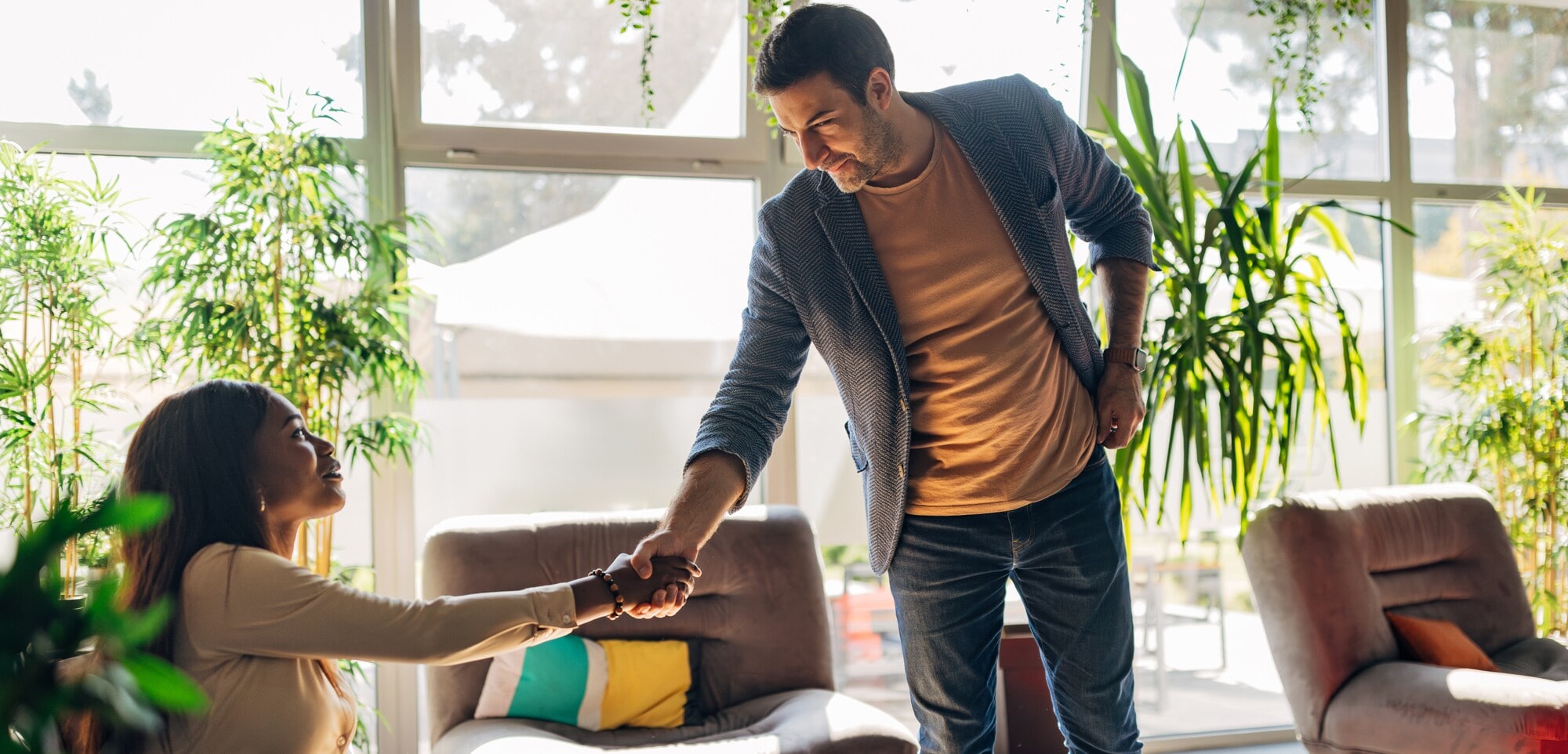 Smart Casual: Lässig, aber top gestylt. Eine Frau und ein Mann in Smart Casual Kleidung begrüßen sich in einem modernen, begrüntem Büro.