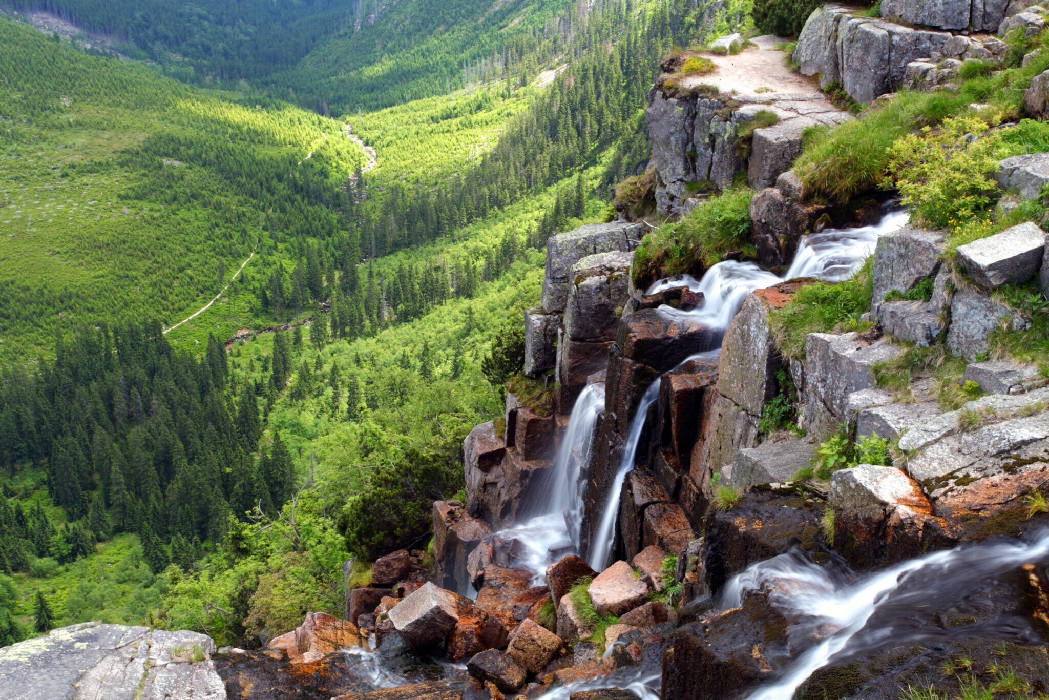 Ein mehrstufiger Wasserfall in einer bewaldeten Berglandschaft. Ein mehrstufiger Wasserfall in einer bewaldeten Berglandschaft.