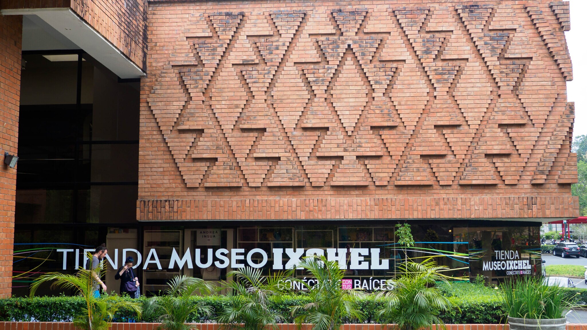 Fassade des Tienda Museo Ixchel mit Ziegelmuster in Form von Dreiecken und Pflanzen davor Fassade des Tienda Museo Ixchel mit Ziegelmuster in Form von Dreiecken und Pflanzen davor