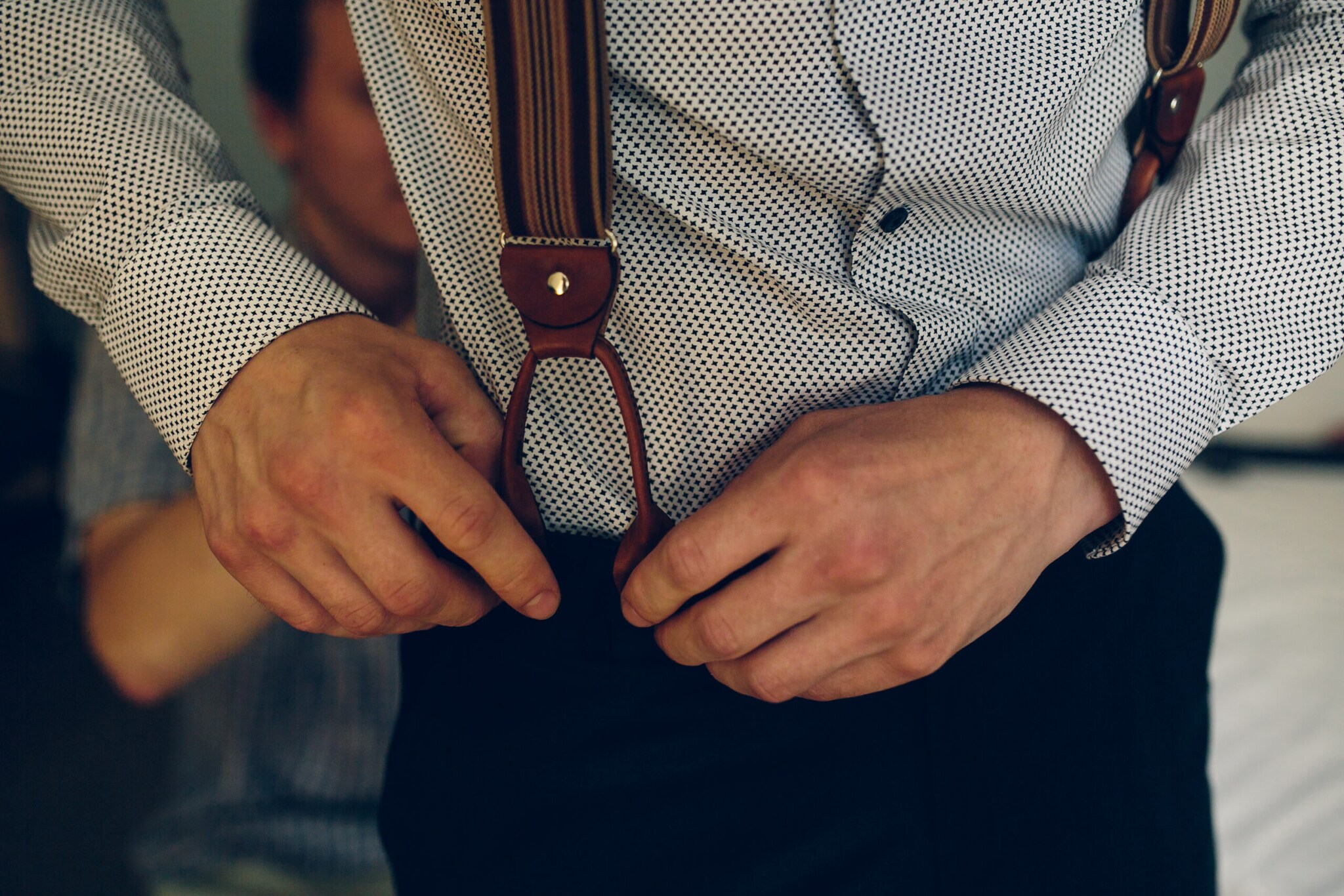 Ein Mann legt ein Paar Hosenträger mit Schlaufen an.