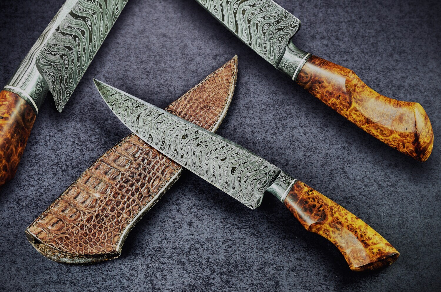 Drei Damastmesser aus Stahl mit Horngriffen und Lederetui