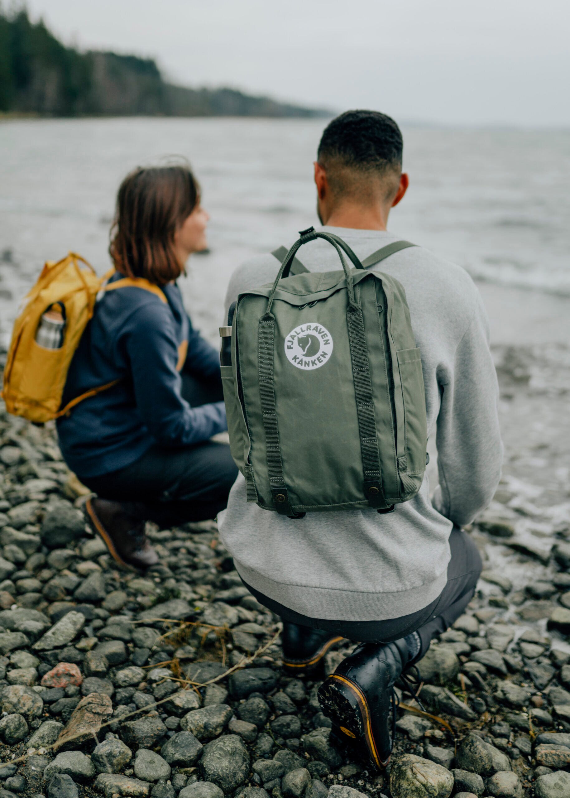 Rückansicht von Frau und Mann mit Rucksäcken am Meer