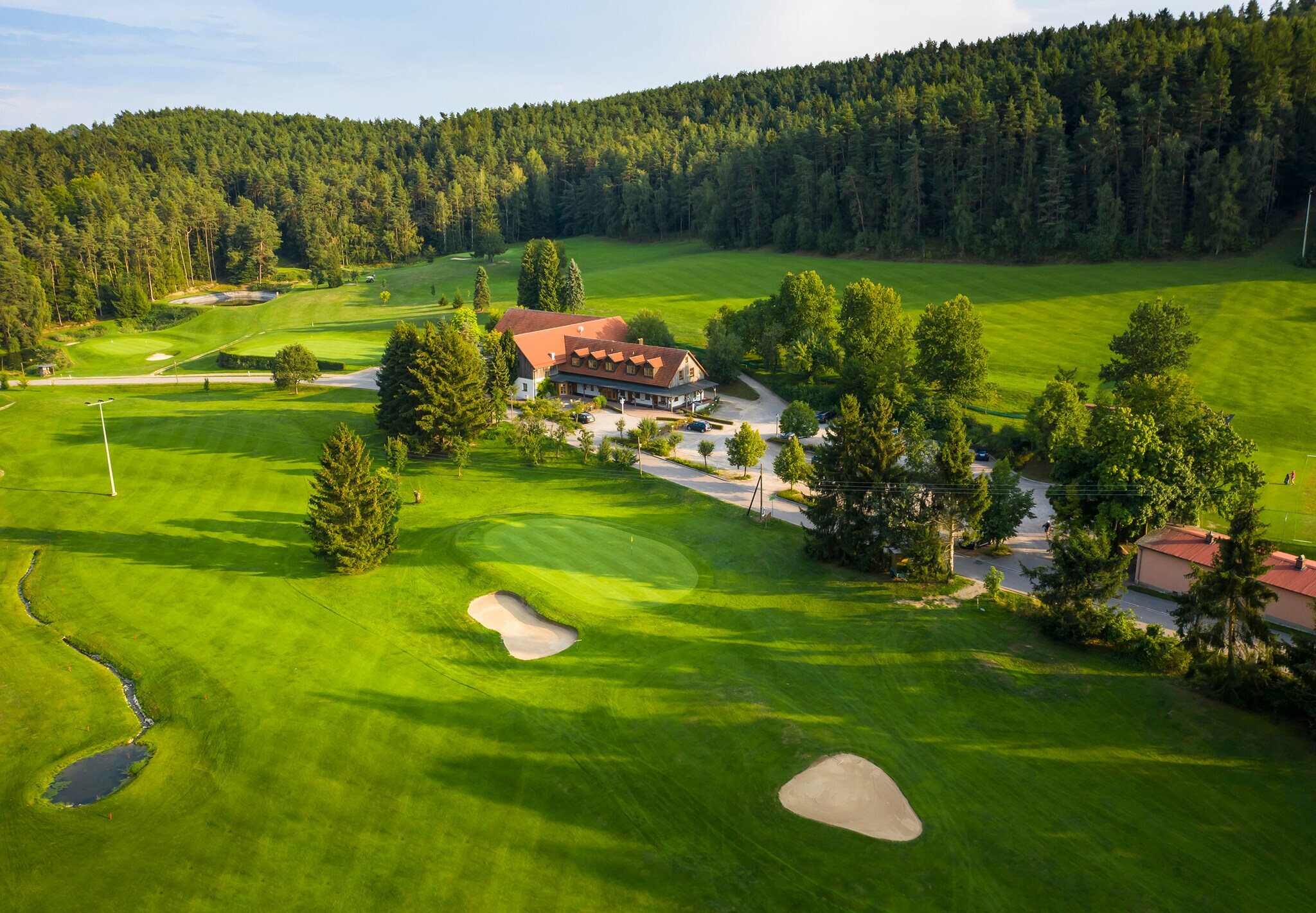 Blick auf Anwesen umgeben von Golfplatz mit Wald im Hintergrund