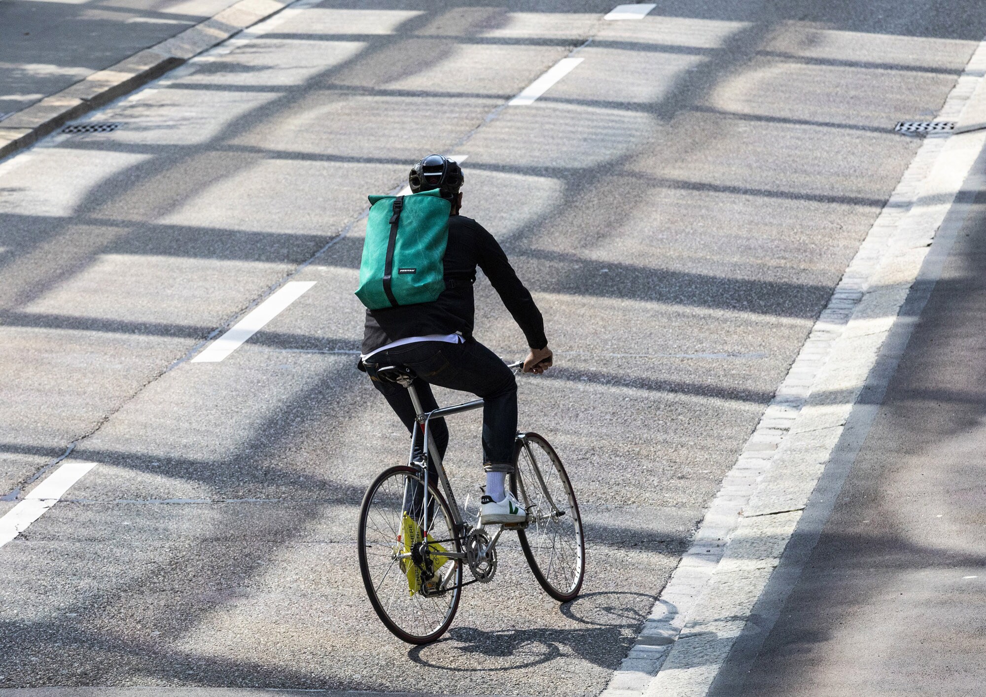 Ein Radfahrer fährt auf der Straße und trägt dabei einen Rucksack von FREITAG.