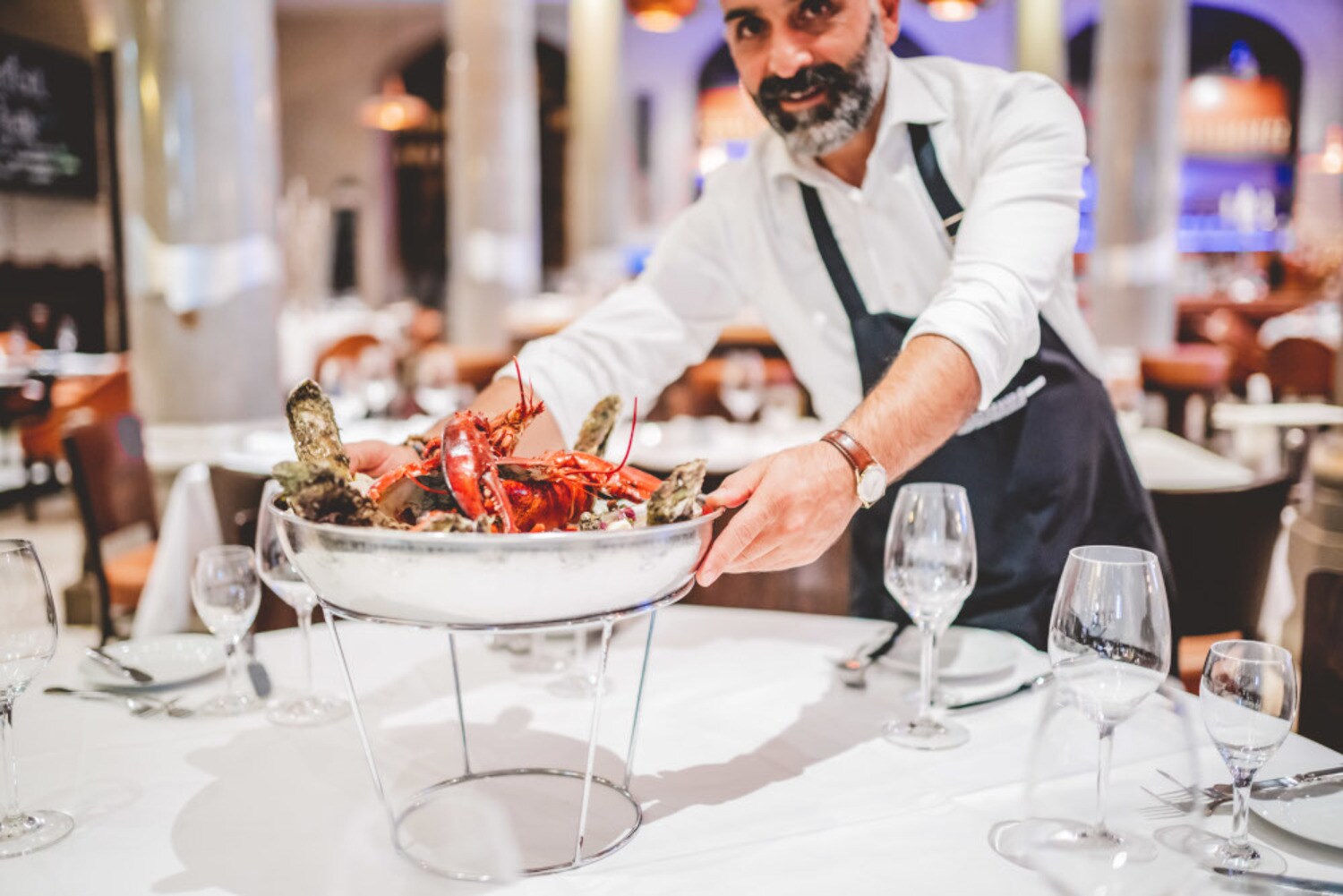 Kellner serviert eine große Schale mit Austern und Meeresfrüchten