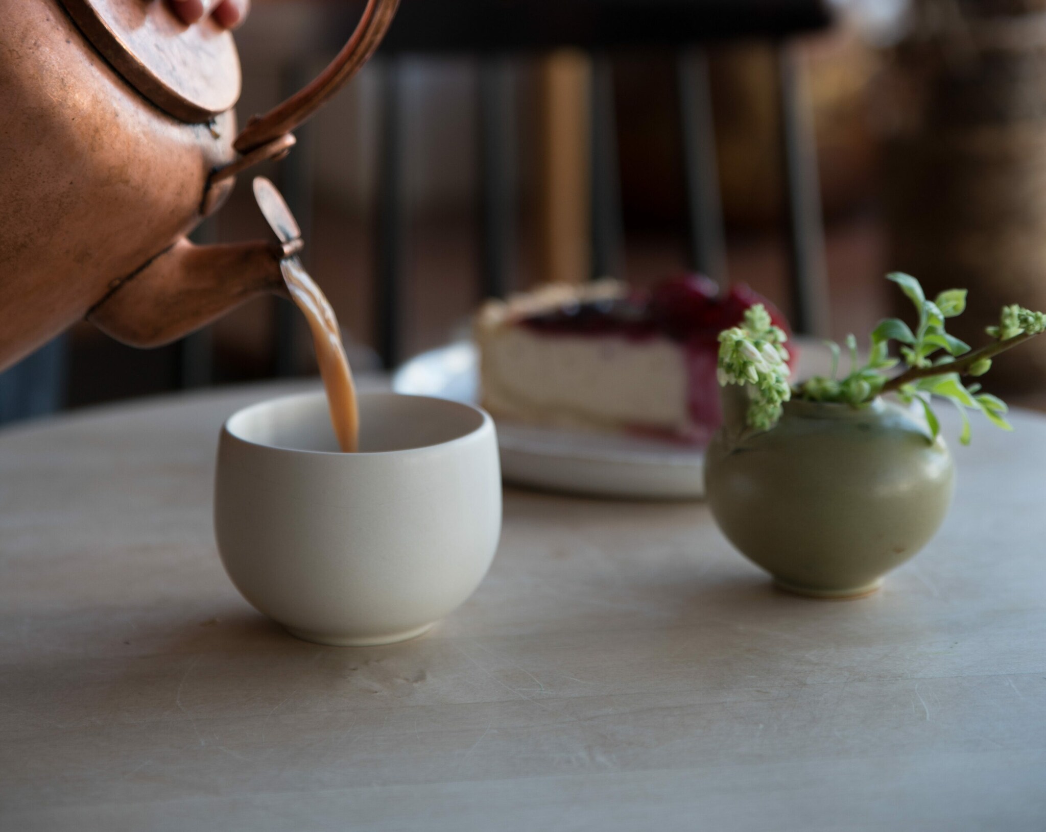 In einen Becher wird Tee aus der Kupferkanne gegossen