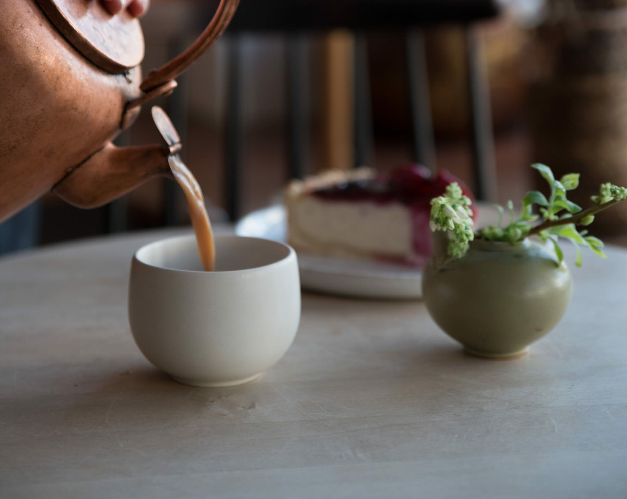 In einen Becher wird Tee aus der Kupferkanne gegossen In einen Becher wird Tee aus der Kupferkanne gegossen