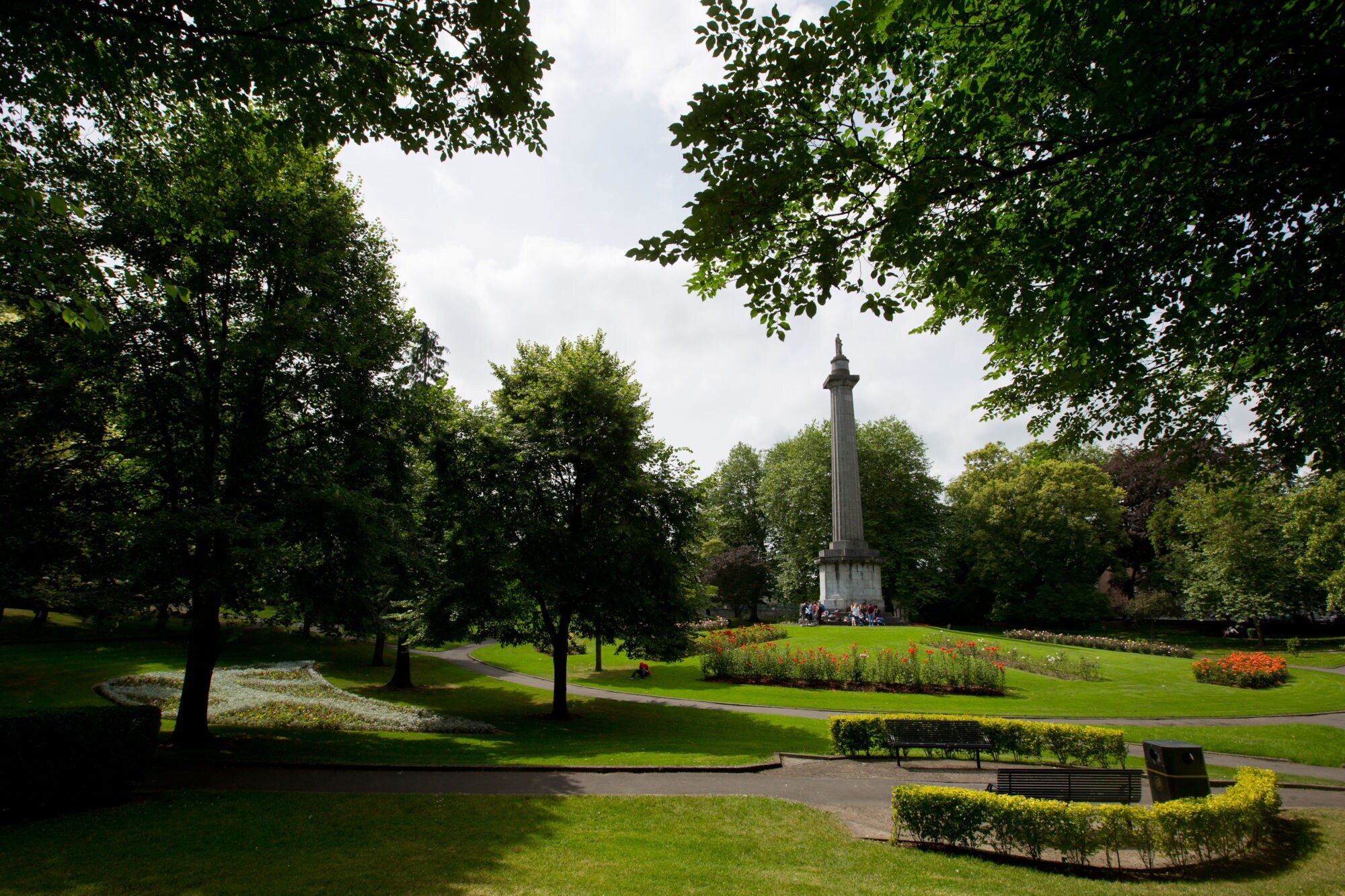 Blick auf den People Blick auf den People's Park in Limerick City mit einem hohen Obelisken in der Mitte, umgeben von Bäumen und Blumenbeeten.