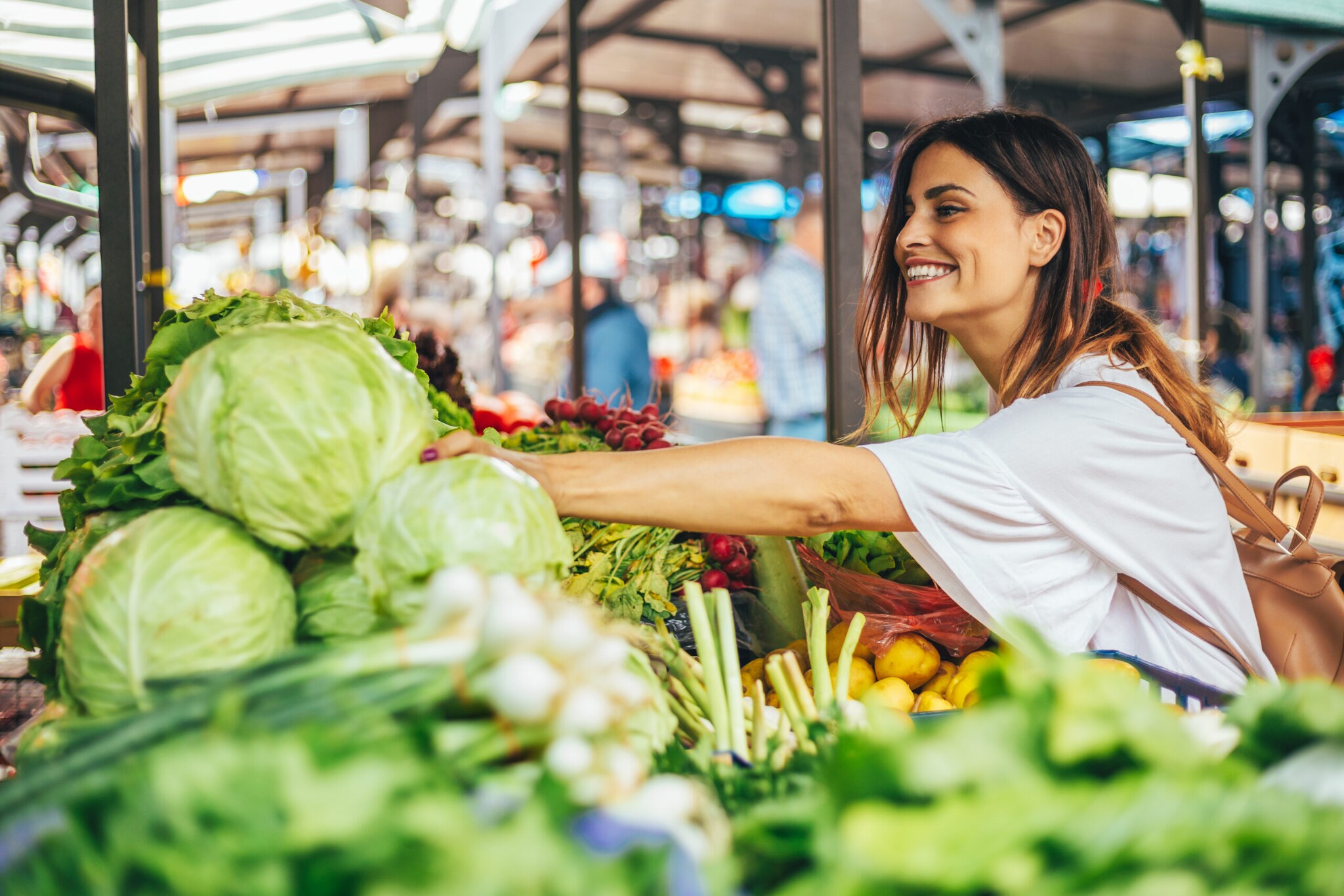 Eine junge Frau kauft Gemüse auf einem Markt.