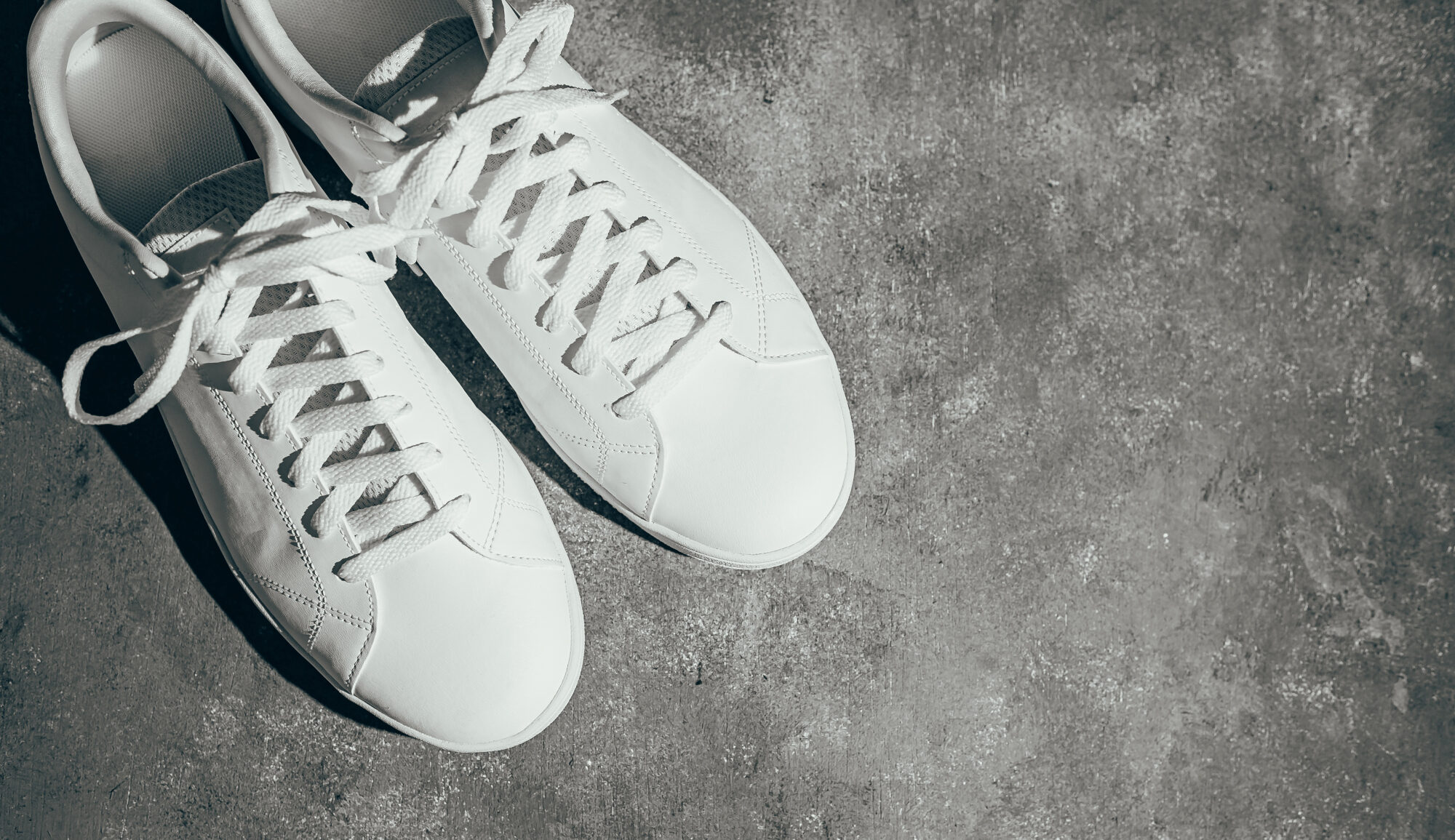 Weiße Turnschuhe auf grauem Untergrund Weiße Turnschuhe auf grauem Untergrund