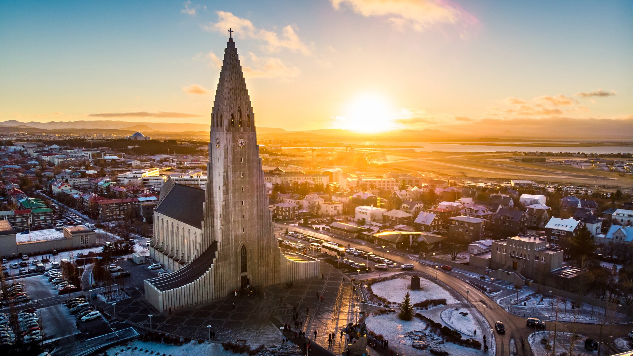 Hallgrímskirkja Kirche in Reykjavík bei Sonnenuntergang mit umliegender Stadt und leicht verschneitem Boden