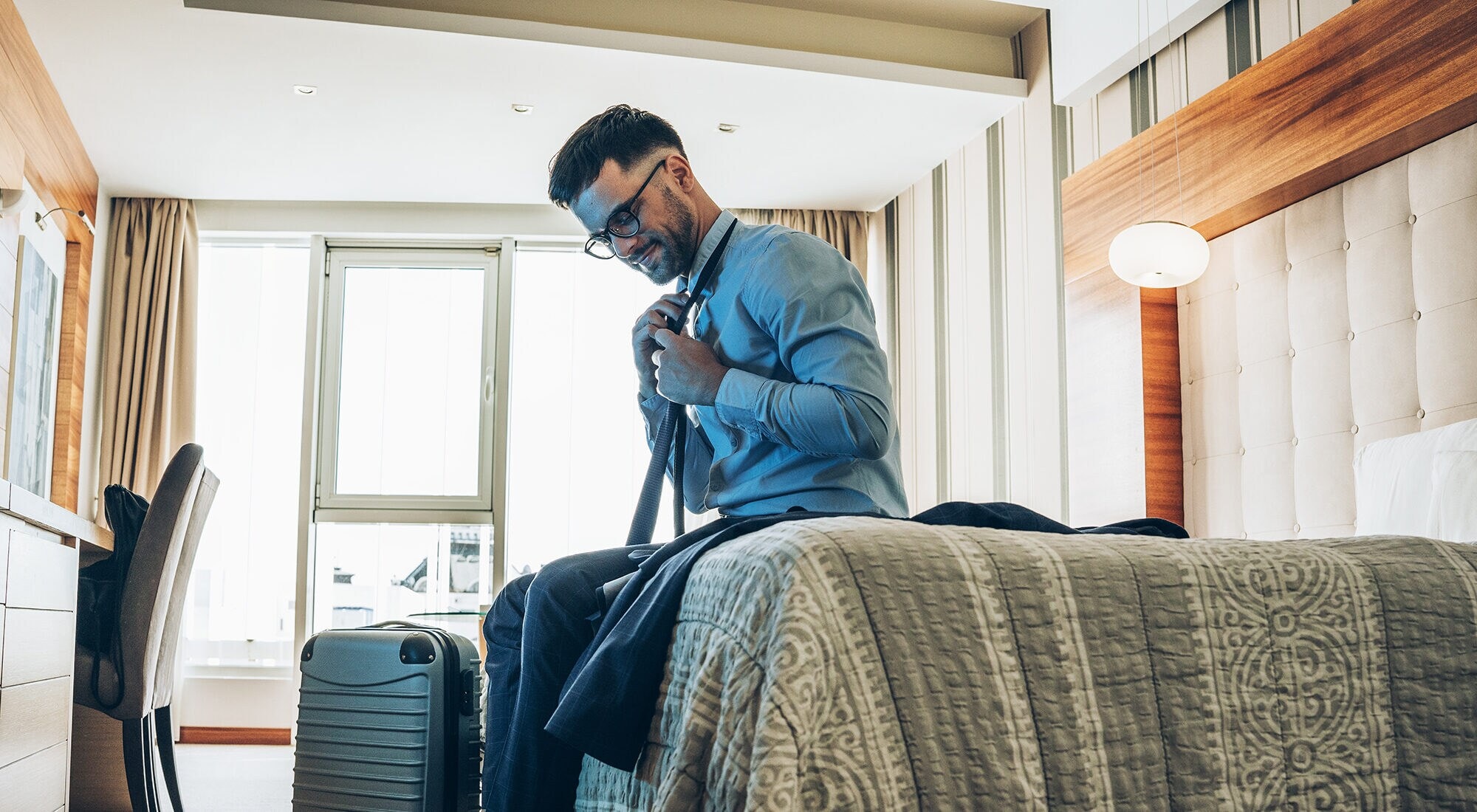 Geschäftmann kommt im Hotelzimmer an und macht es sich gemütlich